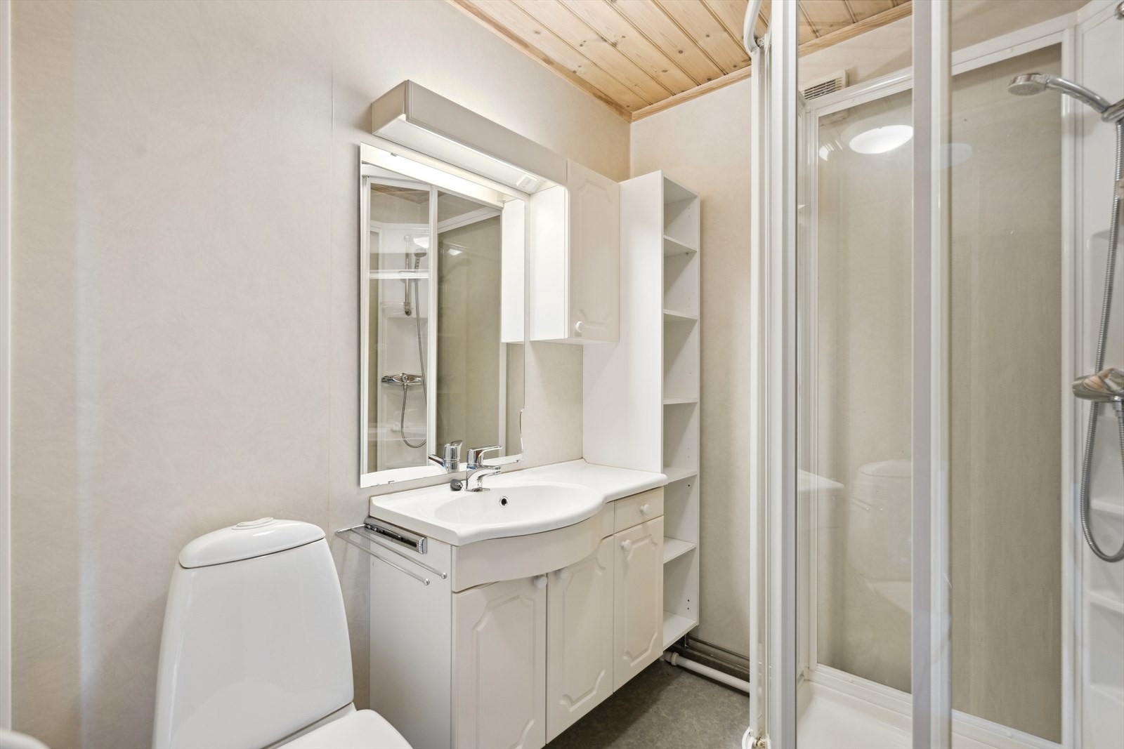 Eldre bad meg belegg på gulv og våtromstapet på vegger. Innredet med baderomsinnredning, toalett og dusjkabinett. Galleribilde