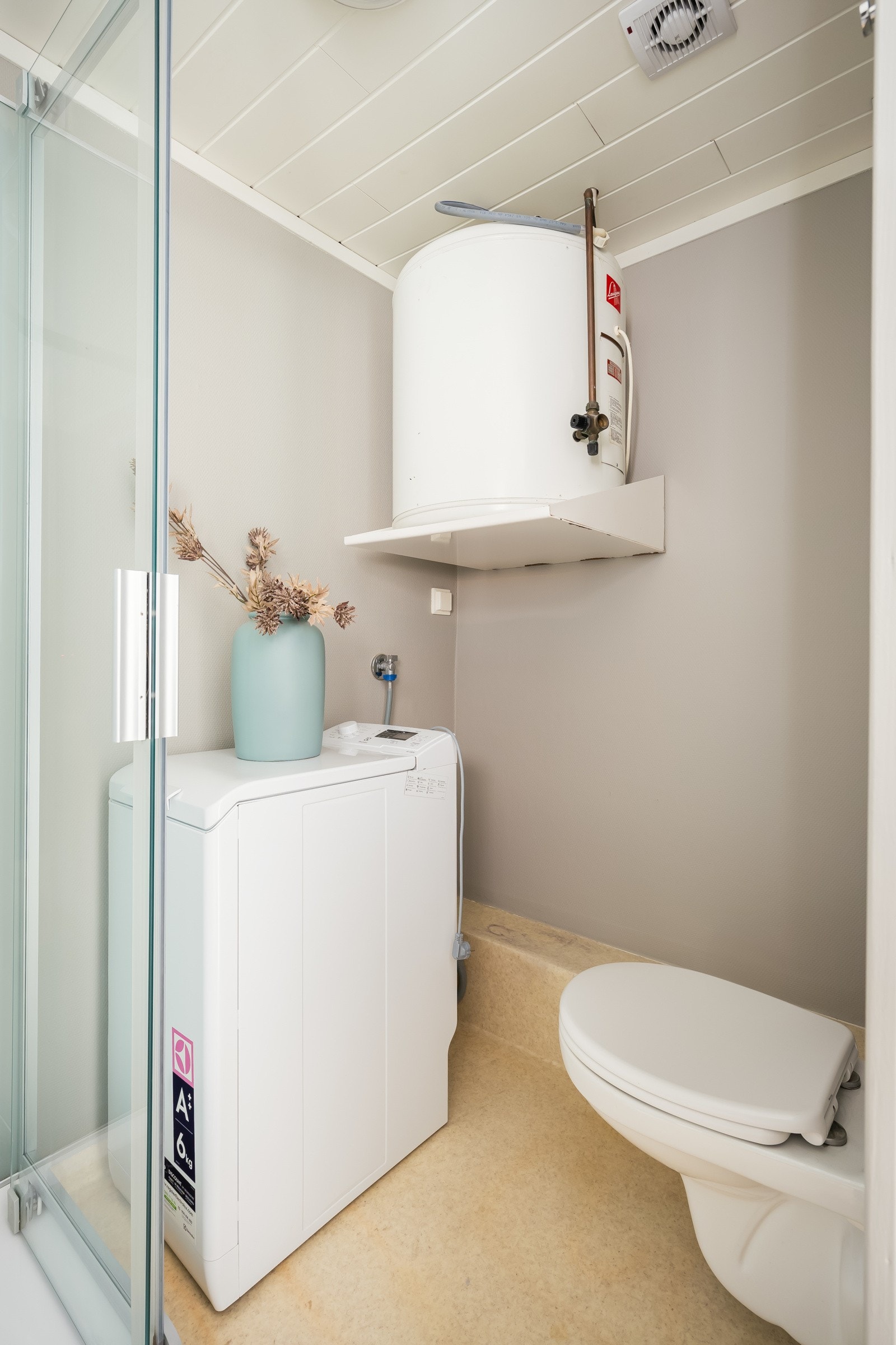 Badet er utstyrt med gulvvarme, dusjkabinett, servant, opplegg for vaskemaskin, varmtvannstank og vegghengt toalett. Galleribilde