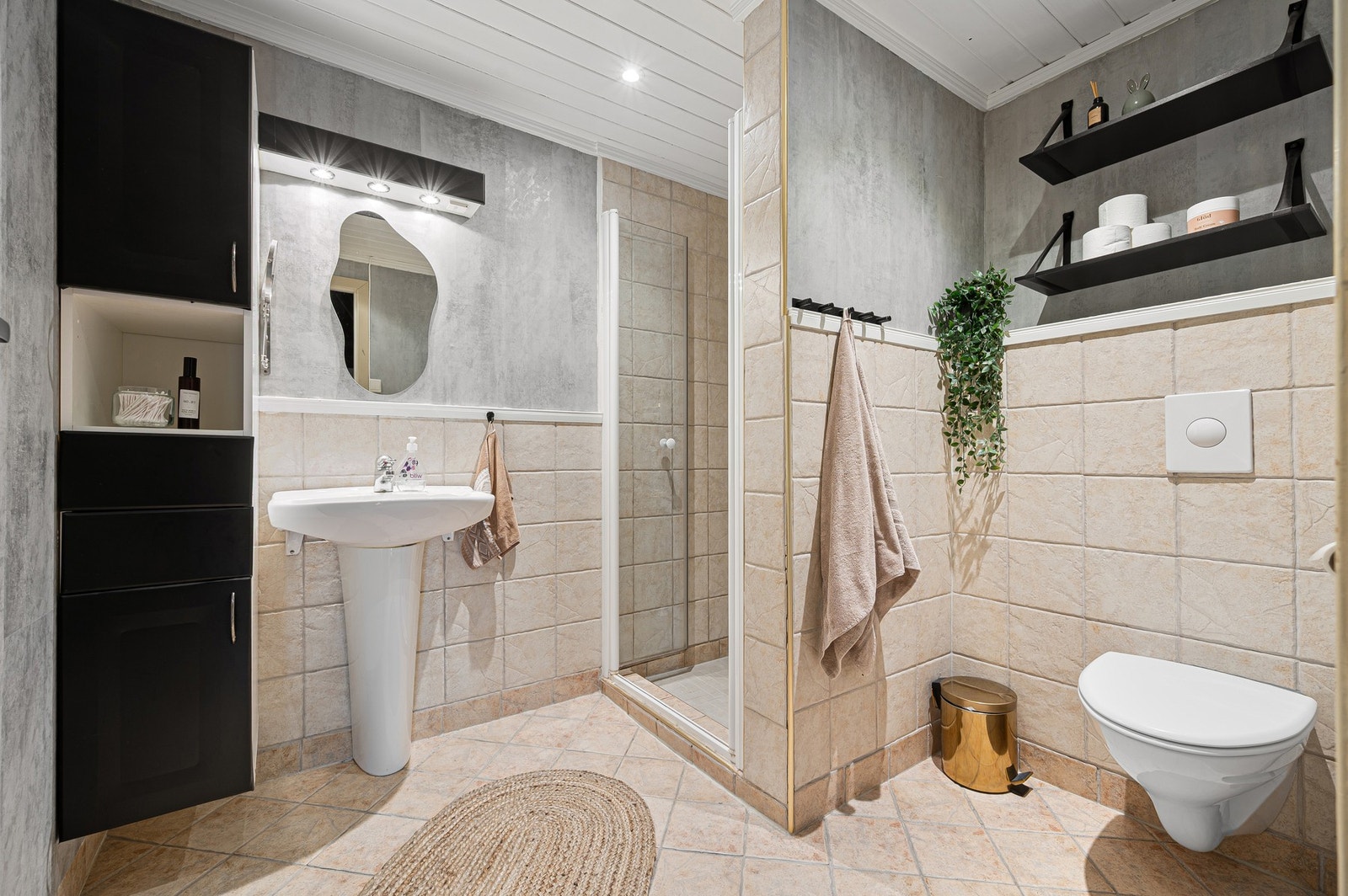 Pent flislagt baderom med downlights i himling og vegghengt høyskap. Galleribilde