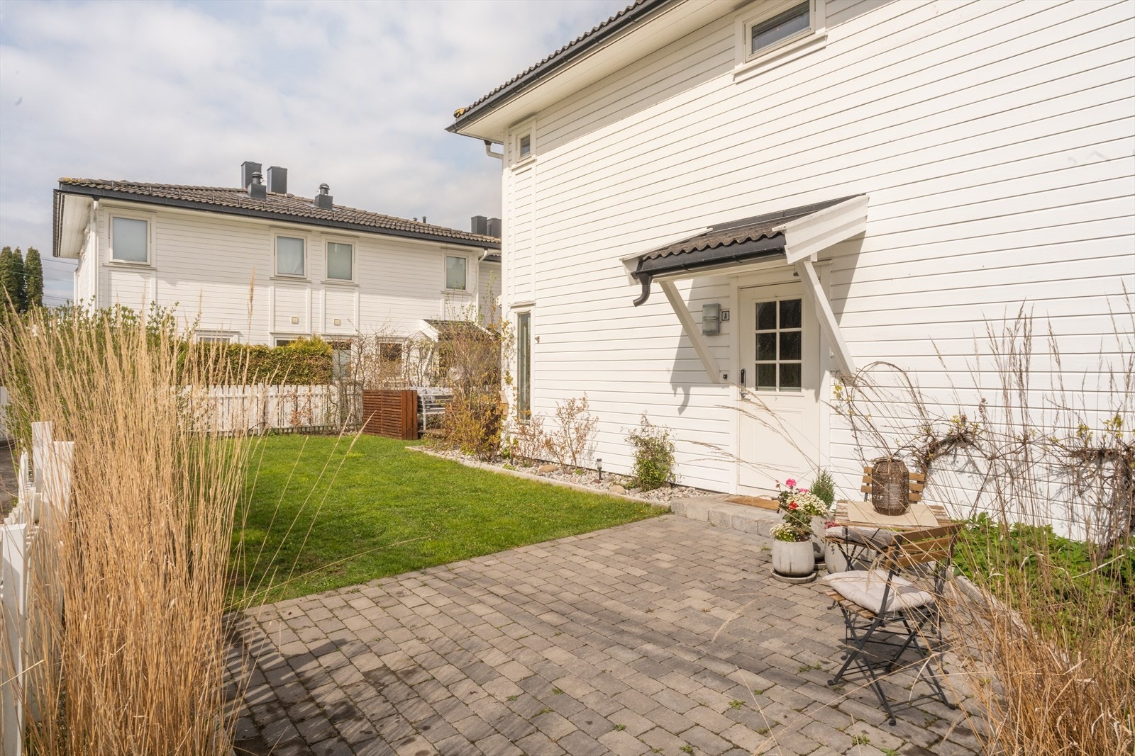 Pent brosteinsbelagt gårdsplass, hvor du kan nyte morgensolen. Frodig og lettstelt hage, med variert beplantning og spiselige vekster som drue og blåbær Galleribilde