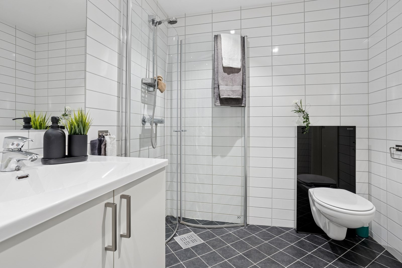 Moderne bad med downlights i himling og praktisk innredning med servant og underskap. Galleribilde