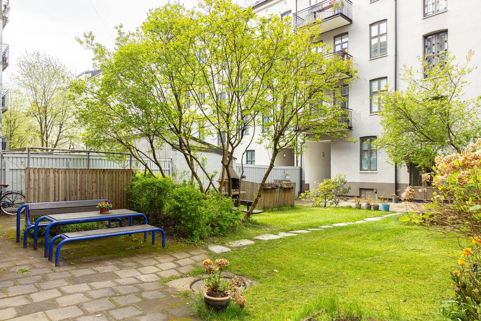 Vakker, opparbeidet bakgård med sittegrupper, beplantning og plen. Galleribilde