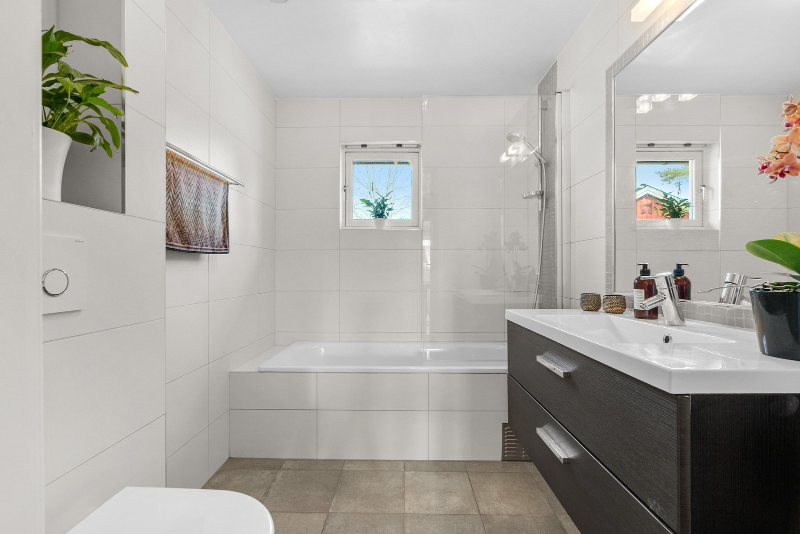 Pent flislagt bad med varme i gulv. På dette badet er det innebygd badekar med dusjutstyr og termostatstyrt blandebatteri. Til glede for store og små! Galleribilde