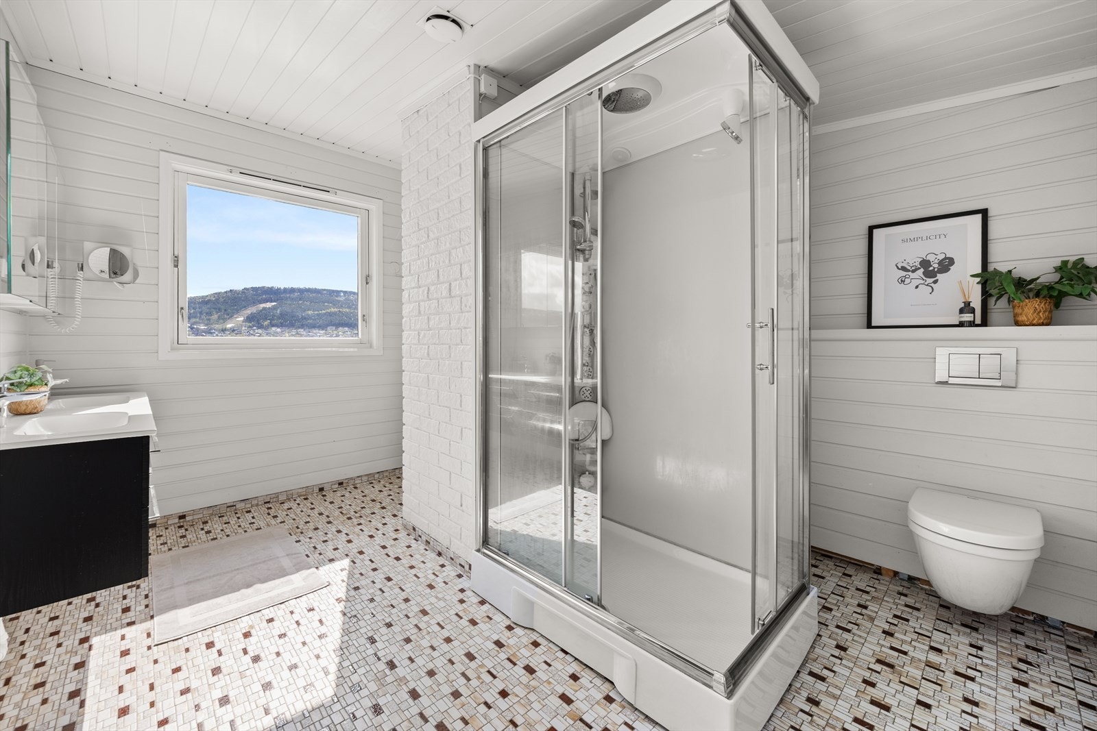 Badet er utstyrt med dobbel servant med underskap, speilskap, stort dusjkabinett og vegghengt toalett Galleribilde