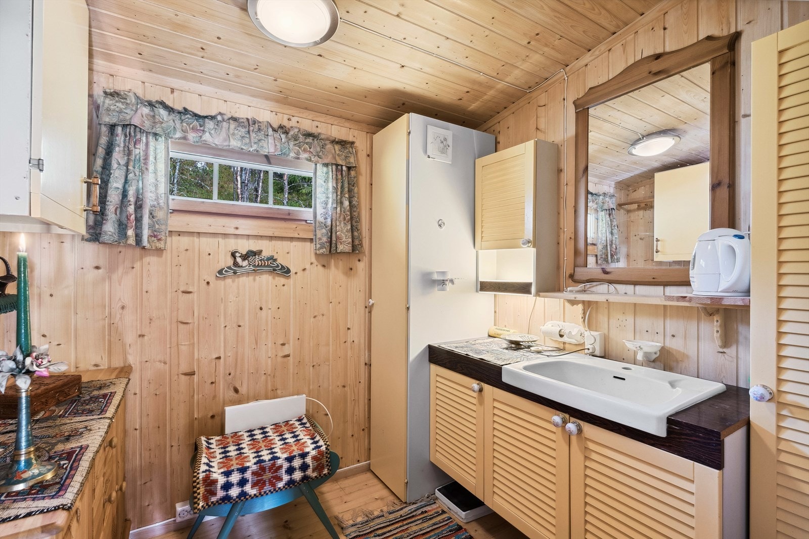 Enkelt vaskerom med skapinnredning med utslagsvask med avløp til bøtte. Galleribilde