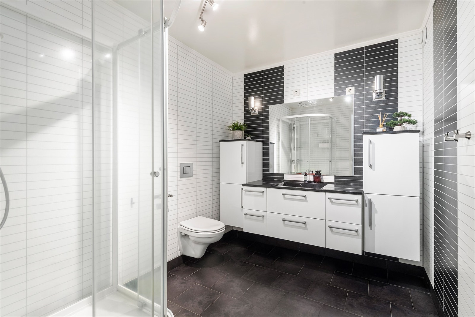 Lyst bad med baderomsinnredning, vegghengt toalett og dusjkabinett Galleribilde