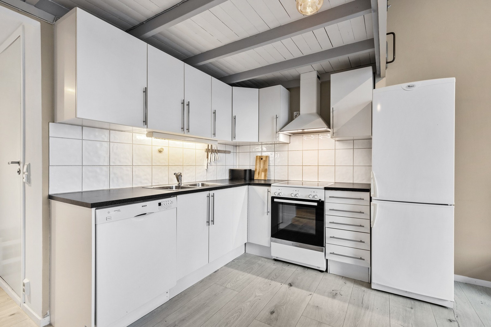 Kjøkkenet er utstyrt med frittstående komfyr, oppvaskmaskin og kjøleskap med fryser, samt vegghengt ventilator Galleribilde