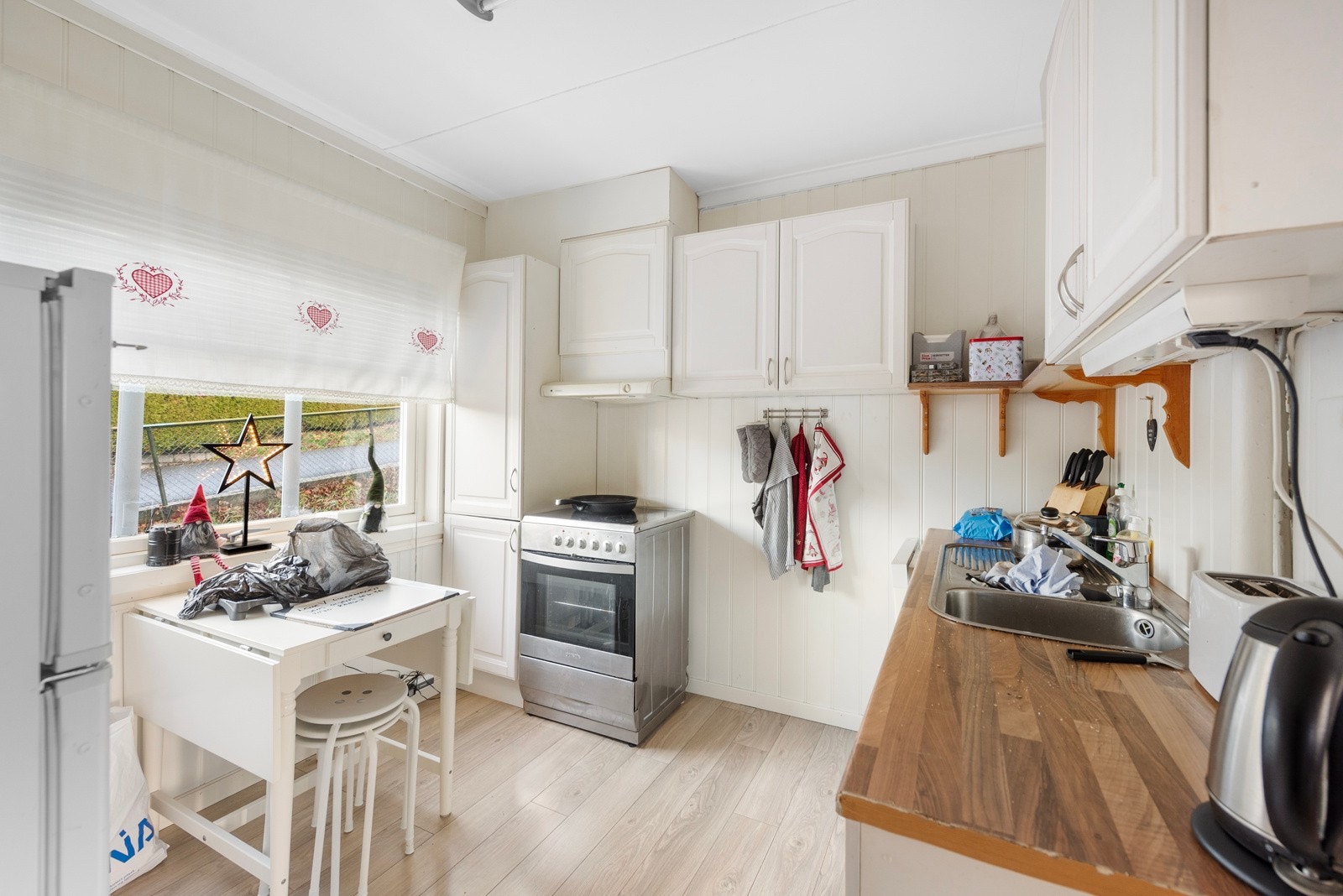 Dette kjøkkenet har lyse, tidløse profilerte fronter og god plass til spisebord Galleribilde