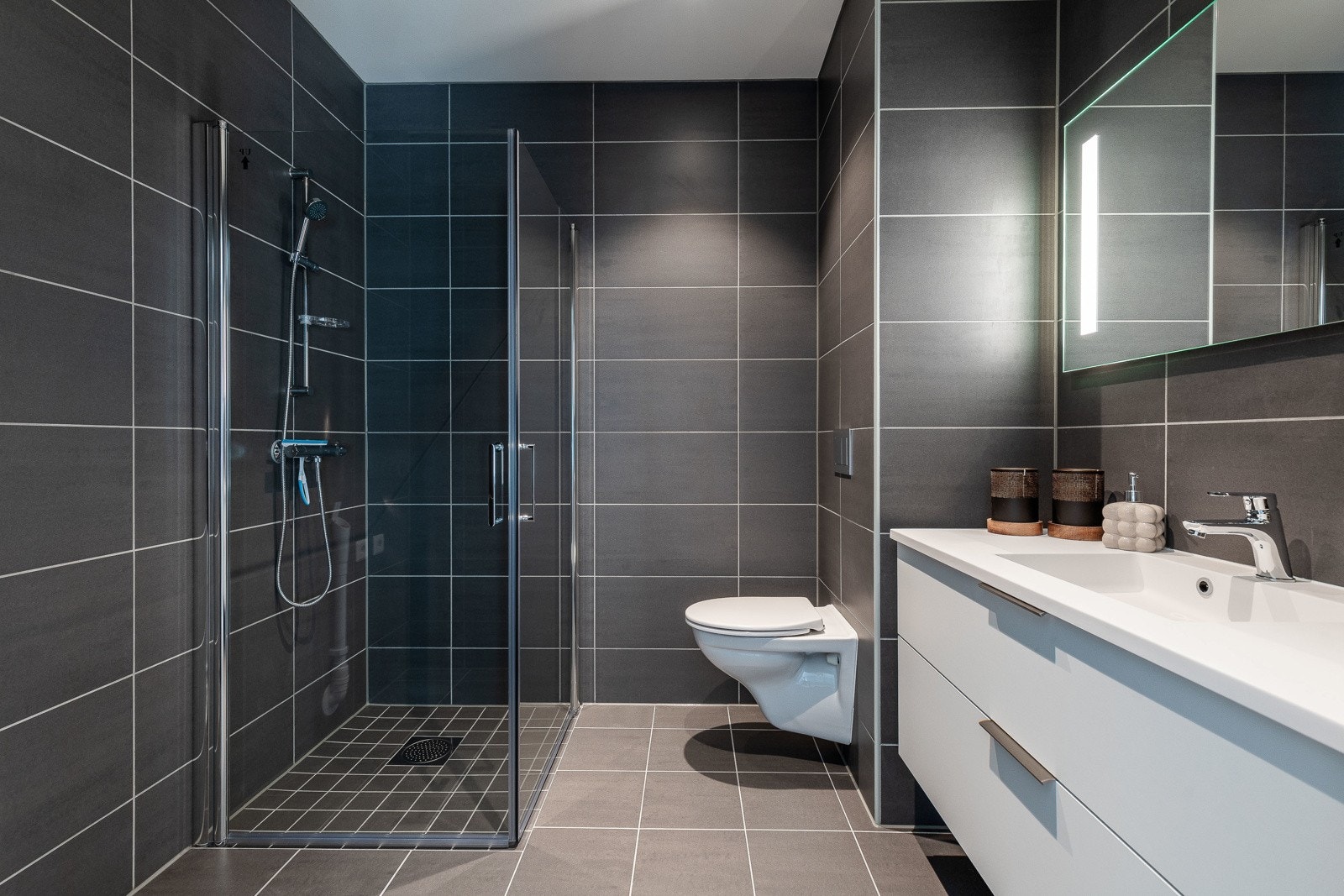 Lekkert flislagt bad i mørk utførelse. Galleribilde