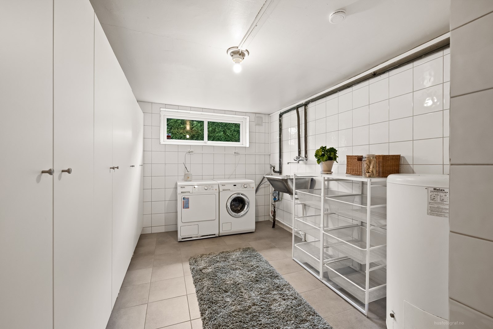 Stort delikat vaskerom i kjeller med fliser på gulv, varmekabler i gulv, skyllekar, varmtvannsbereder og opplegg til vaskemaskin. Det er god skap og garderobeplass på soverom. Galleribilde