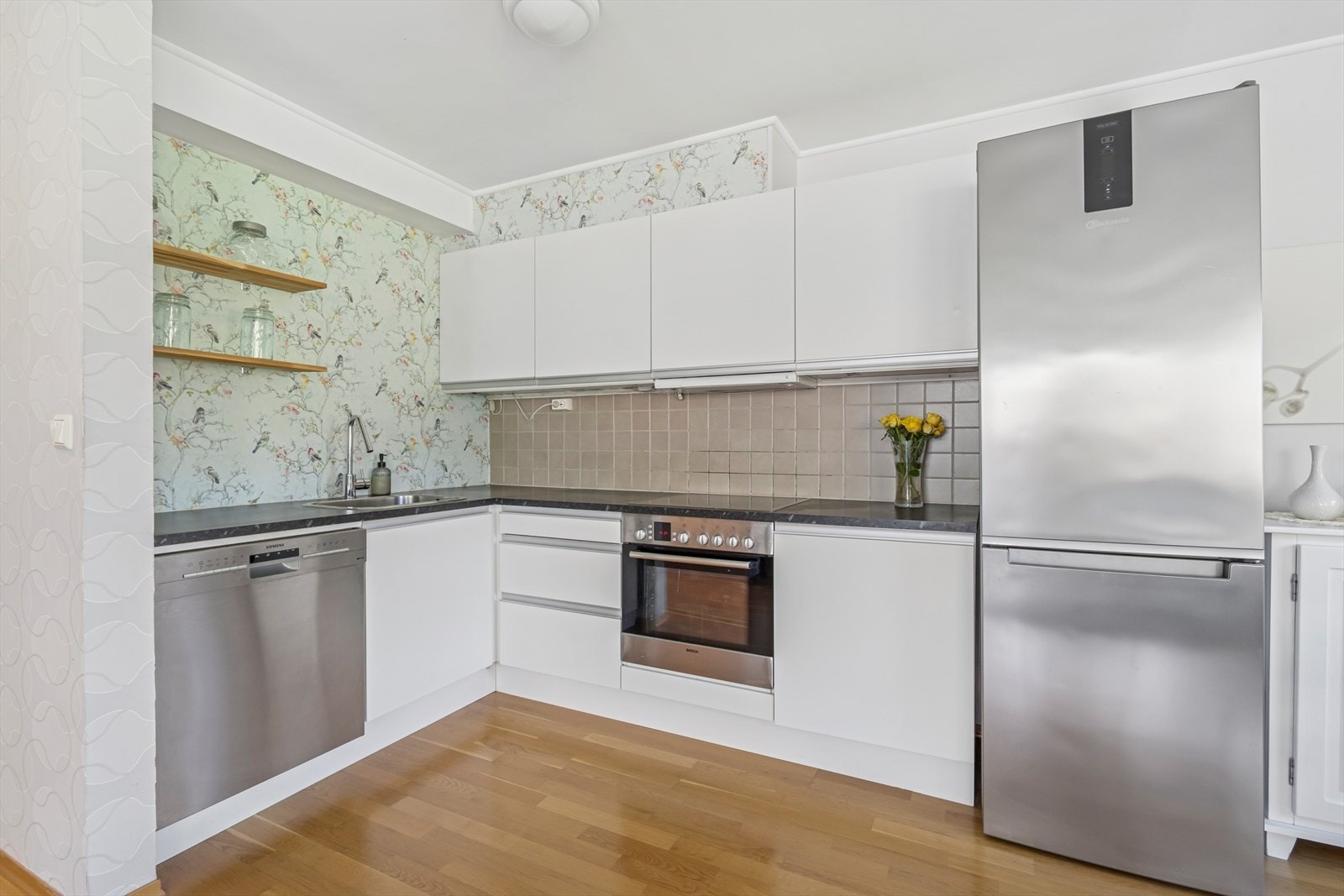 Kjøkkeninnredningen har hvit glatt innredning og laminat benkeplate. Galleribilde