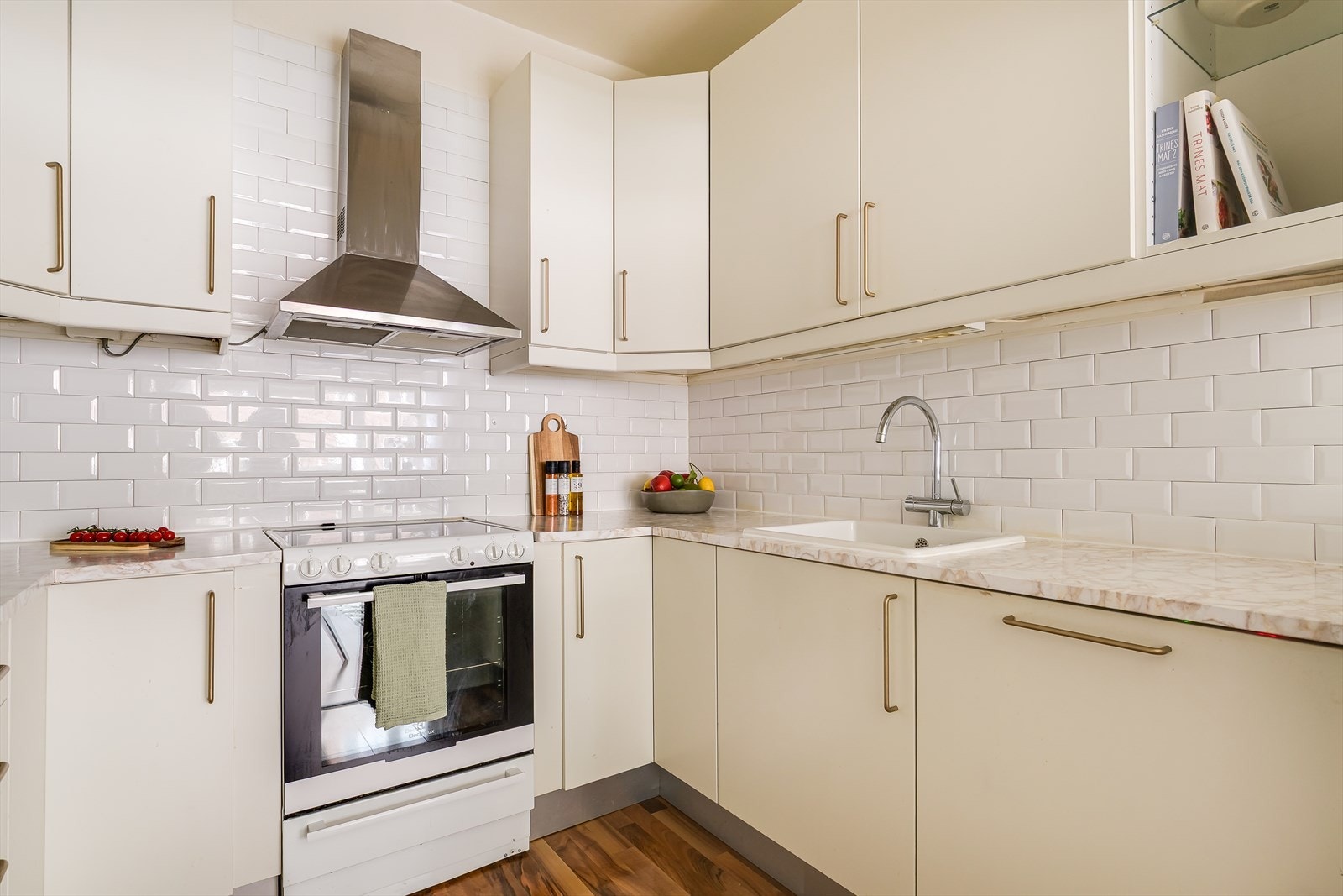 Kjøkkeninnredningen fremstår med glatte fronter, foliert benkeplate med oppvaskkum, lys under overskap, ventilator med kullfilter, integrert oppvaskmaskin og frittstående kombiskap. Galleribilde