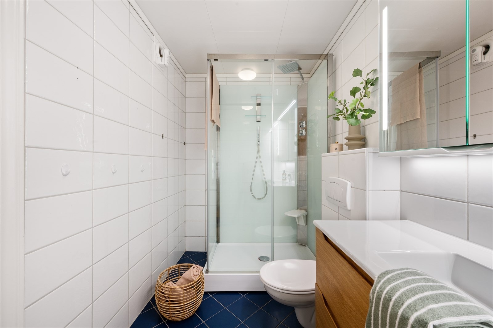 - Badet er innredet med vegghengt toalett, benkeskap med servant, dusjkabinett og speilskap med integrert belysning - Galleribilde