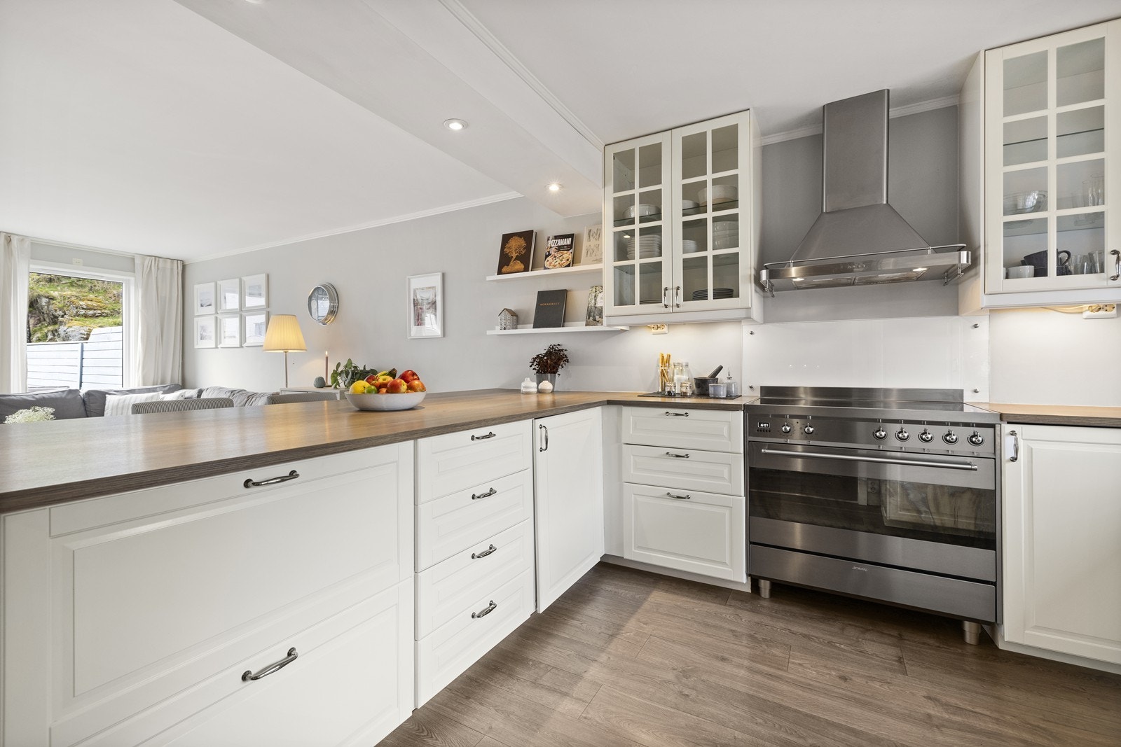 Innredningen framstår klassisk med hvite, profilerte fronter, laminat benkeplate og vitrineskap. Galleribilde