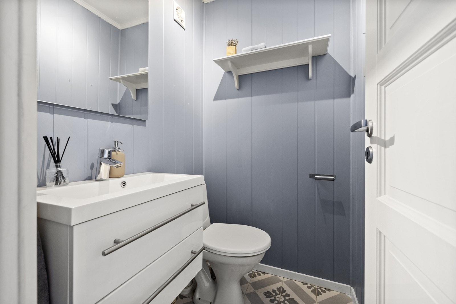 Separat toalettrom med flislagt gulv og panelte overflater. Servant med skuffer, speil og varmekabler i gulv. Galleribilde