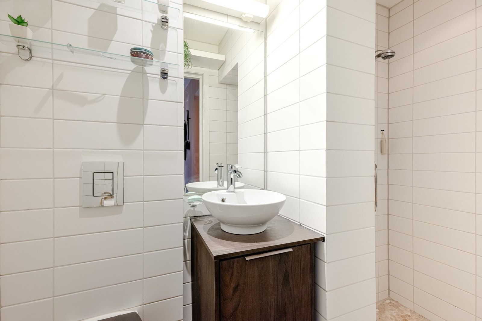 Innredningen består av ovenpåliggende servant på underskap, speil med belysning og vegghengt toalett. Galleribilde