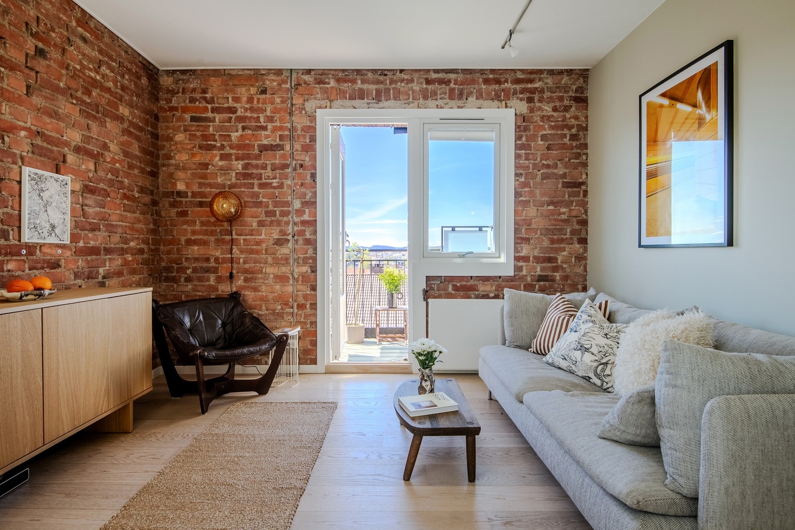 Stuen er et sjarmerende oppholdsrom som kombinerer originale teglsteinsvegger med lyse, malte flater på en stilfull måte. Galleribilde