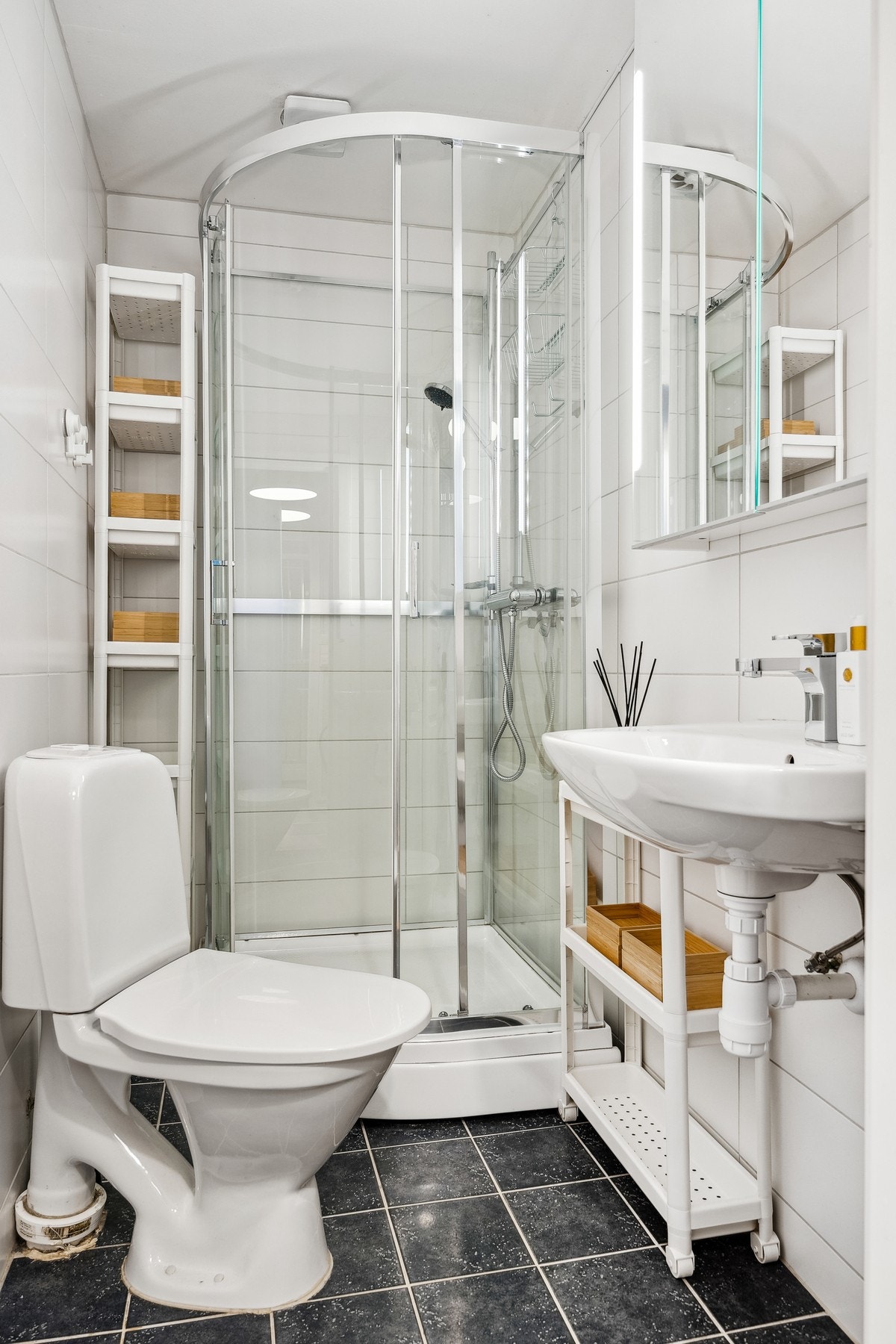 Badet er utstyrt med vegghengt servant, speilskap, dusjkabinett og toalett. Galleribilde