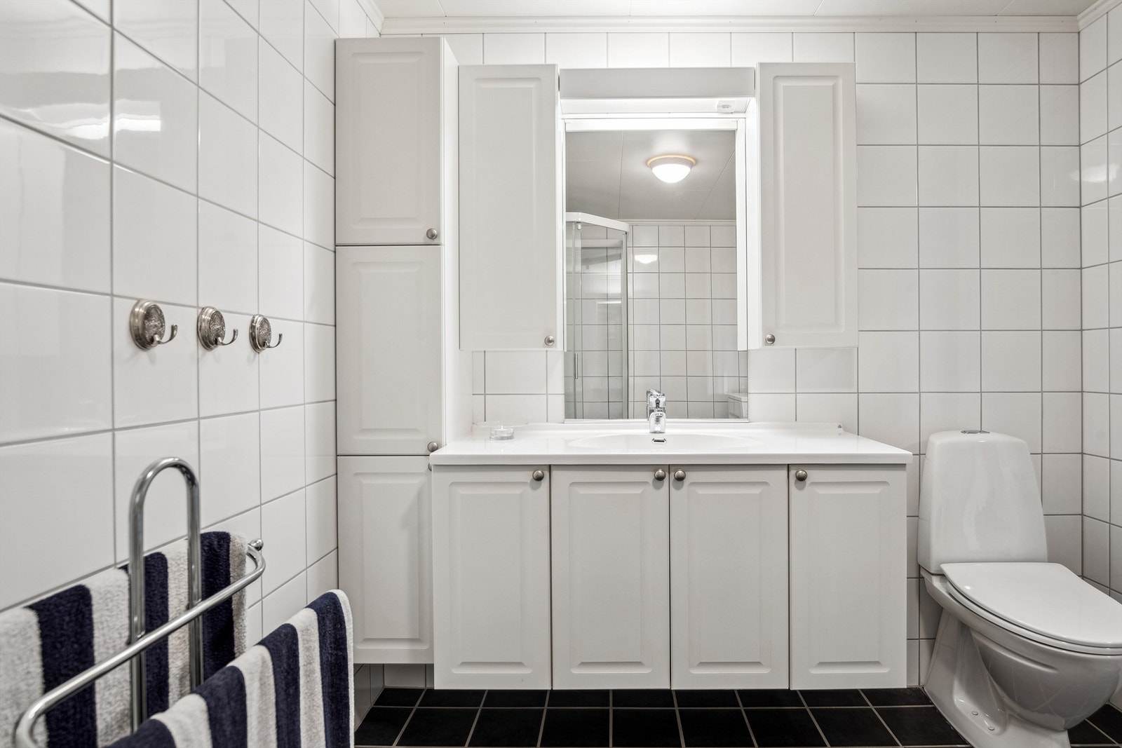 Klassisk baderomsinnredning med heldekkende servantplate og god oppbevaringsplass Galleribilde