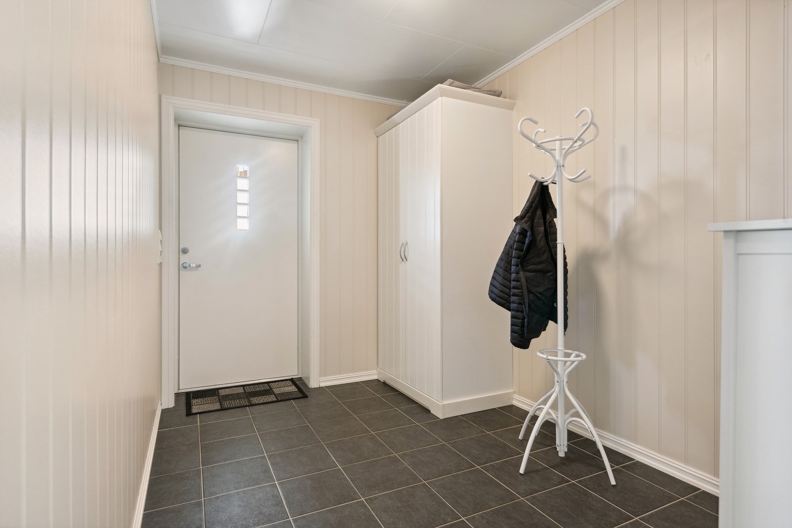 Romslig flislagt entré med garderobeskap Galleribilde