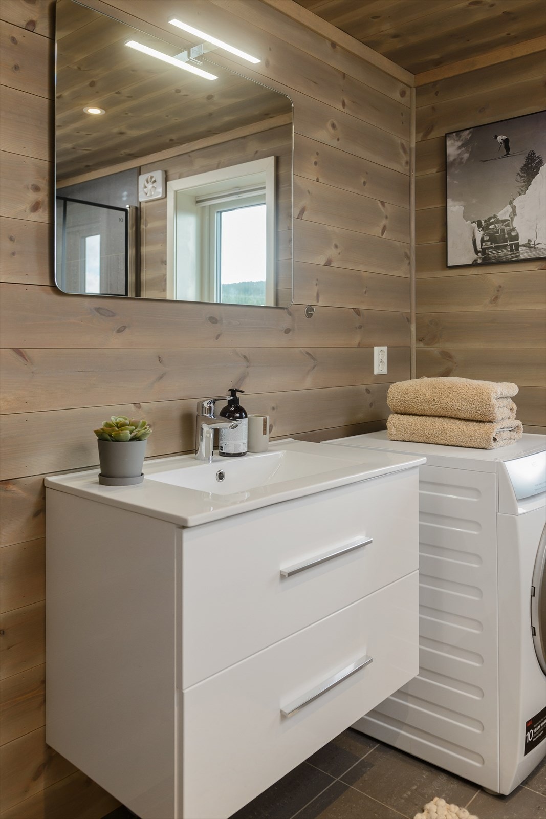 Baderommet er utstyrt med vegghengt servant, dusj direkte på gulvet med dusjvegger, og servant med tilhørende underskap. Galleribilde