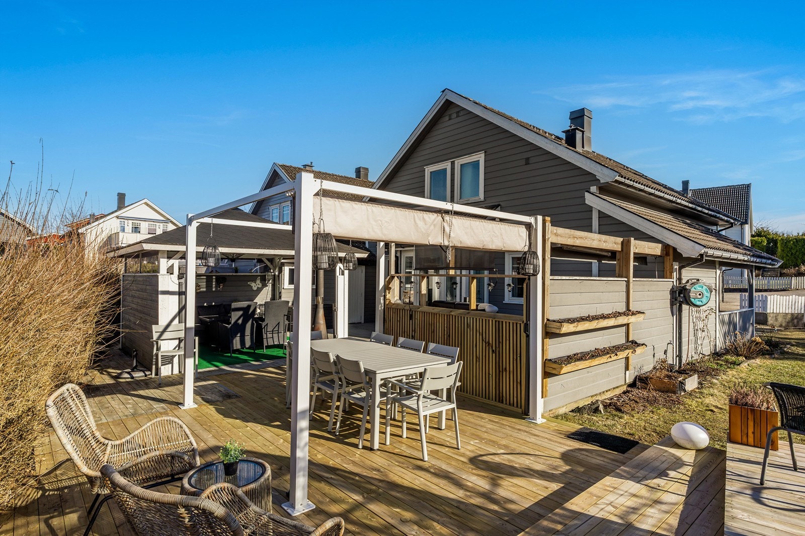 LETTSTELT OASE med overbygget utestue, pergola, utekjøkken, store terrasseflater, drivhus og blomsterbed. Galleribilde