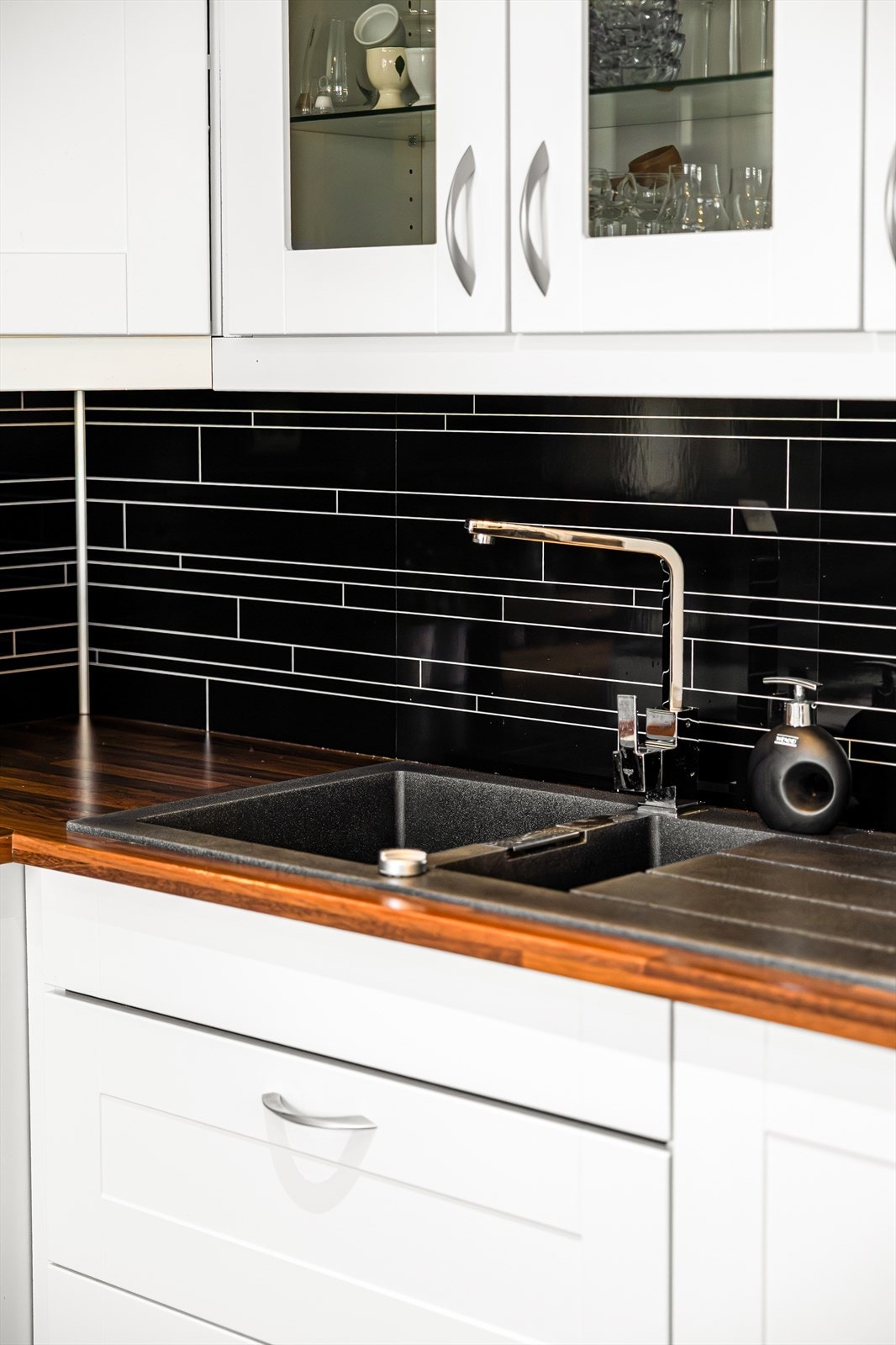 Dobbel vask i sort kompositt matcher veggplatene mellom benken og overskapene. Galleribilde