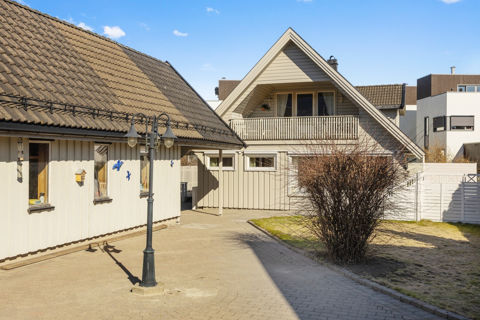 Steinbelagt gårdsplass som leder videre inn til hage og terrasse Galleribilde