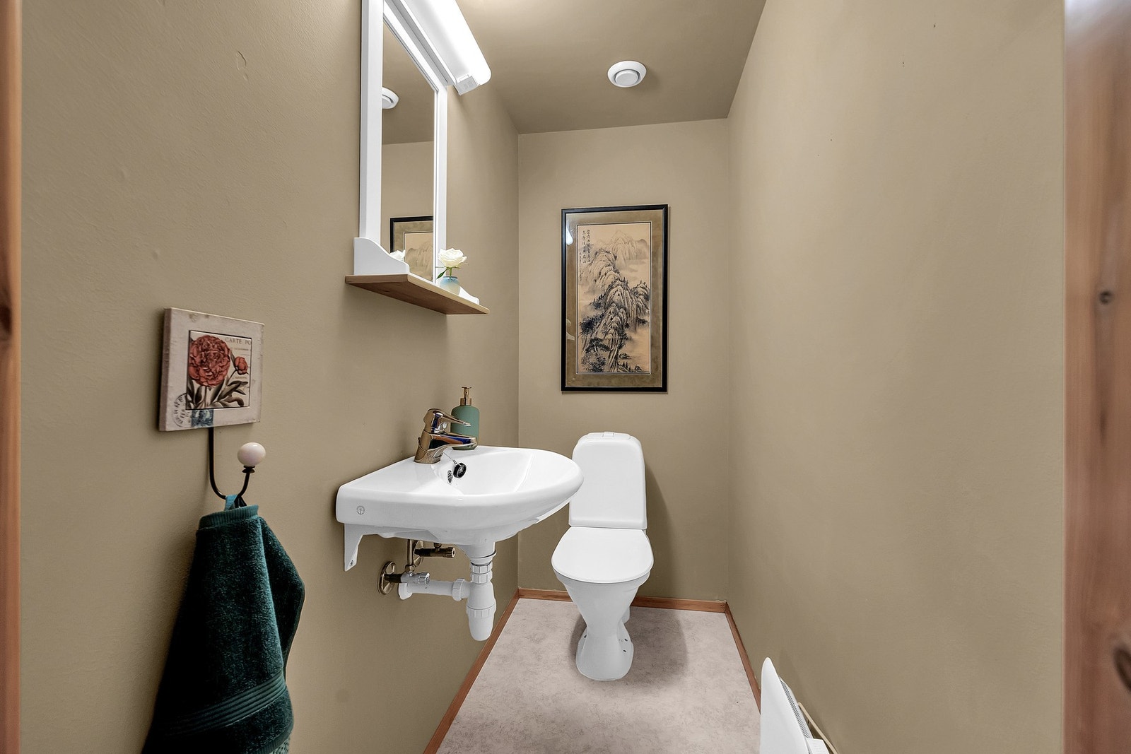 I første etasjen er det en toalettrom med beige/brune vegger og himling, samt linoleum/gulvbelegg. Innredningen består av WC, vegghengte speil og servant med ettgreps blandebatteri. Galleribilde