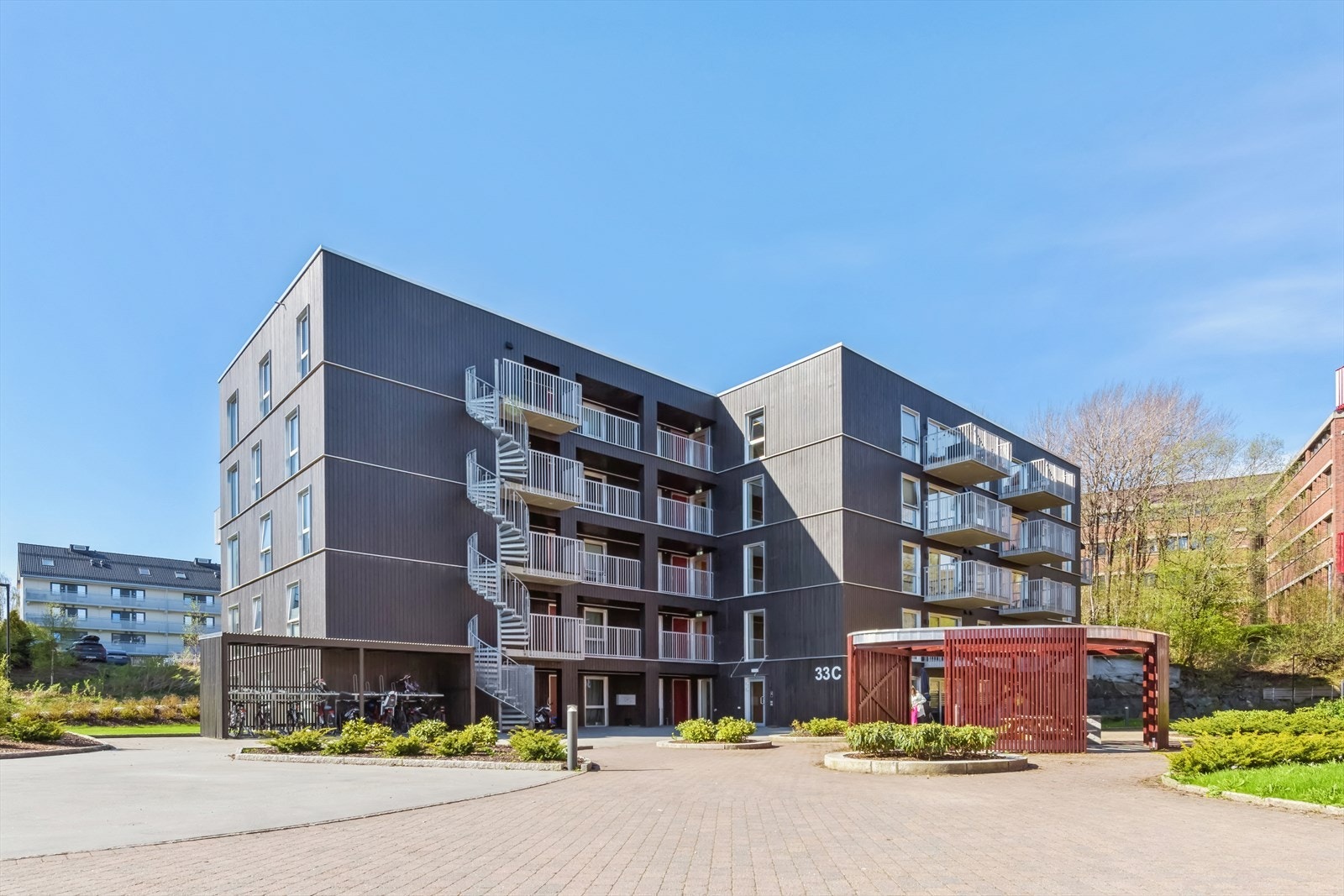 Fasade bakside med inngangsparti. Det er meget åpne og flotte utearealer på sameiets tomt. Sykkelparkering rett ved. Galleribilde
