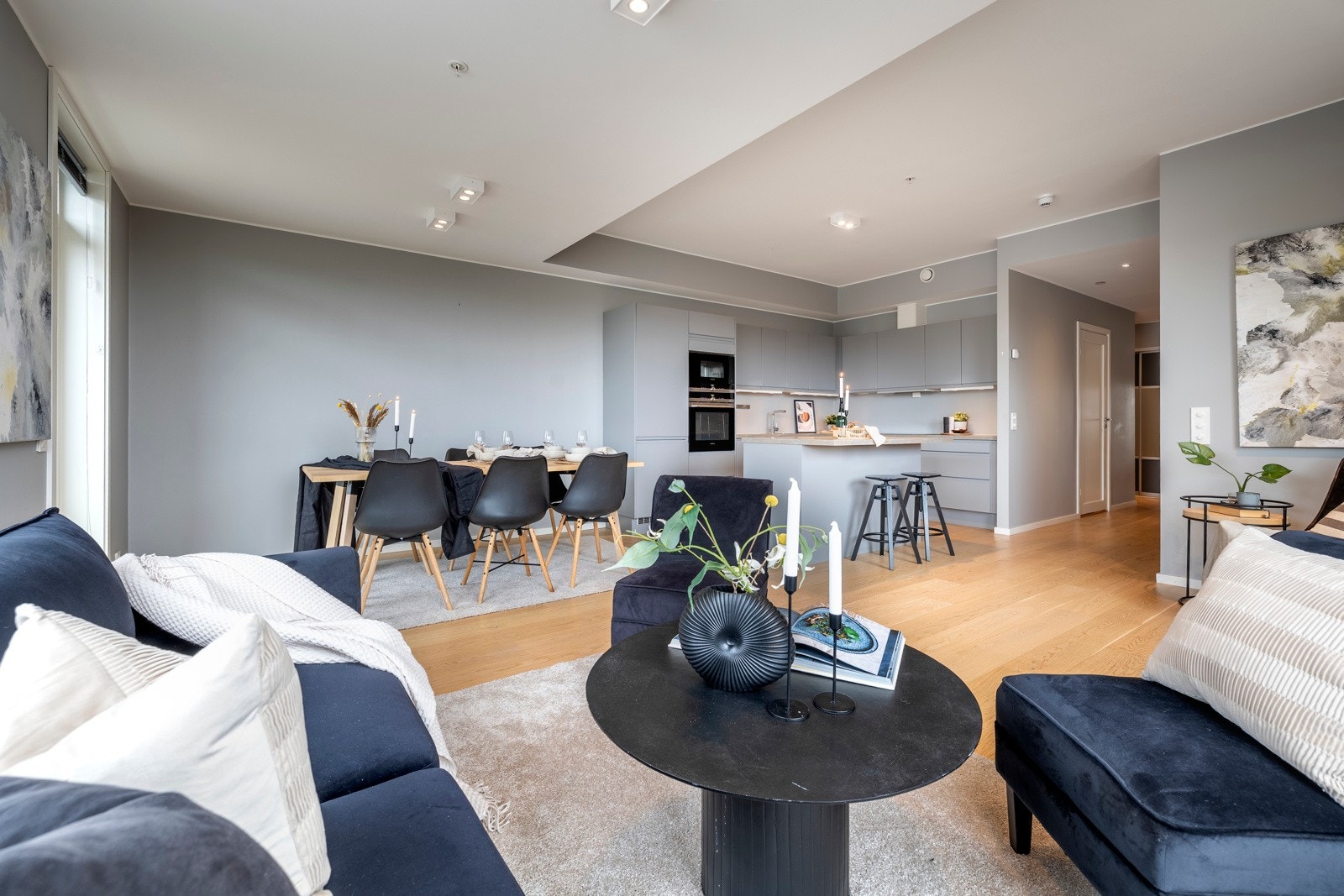 Sonene markeres av nedsenket himling i stuen og noe høyere himling over kjøkkensonen. Det hele rammes inn av pene overflater med enstavs parkettgulv, glatte, gråmalte vegger, nedfelte downlights og vannbåren gulvvarme. Galleribilde