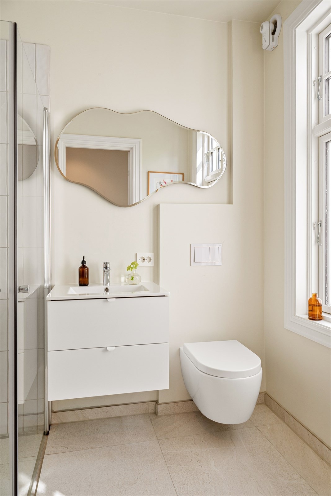 Badet er innredet med servant i baderomsmøbel, veggmontert toalett og dusjhjørne. Galleribilde