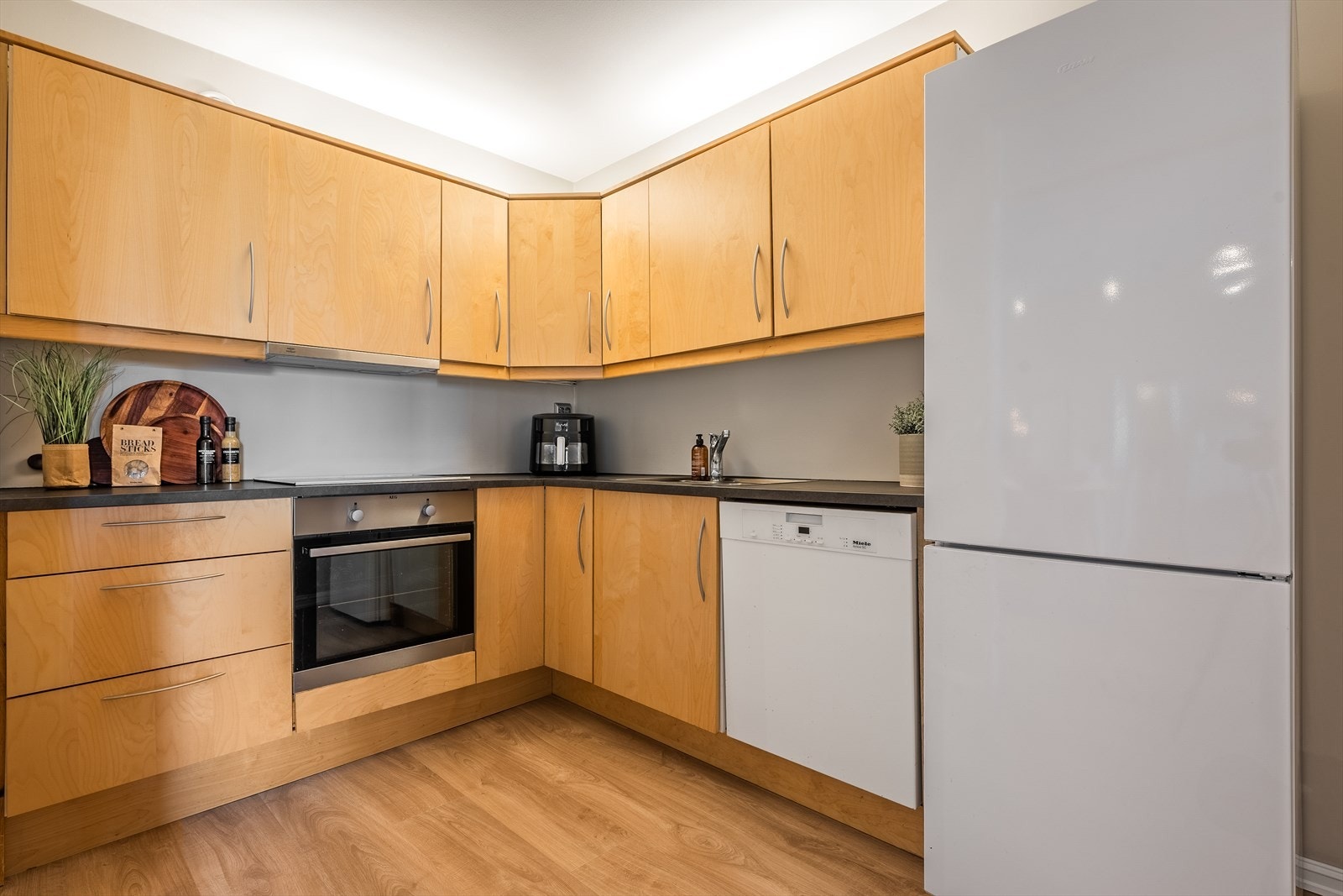 Kjøkkeninnredningen har slette bøkfronter og laminat benkeplate. Galleribilde