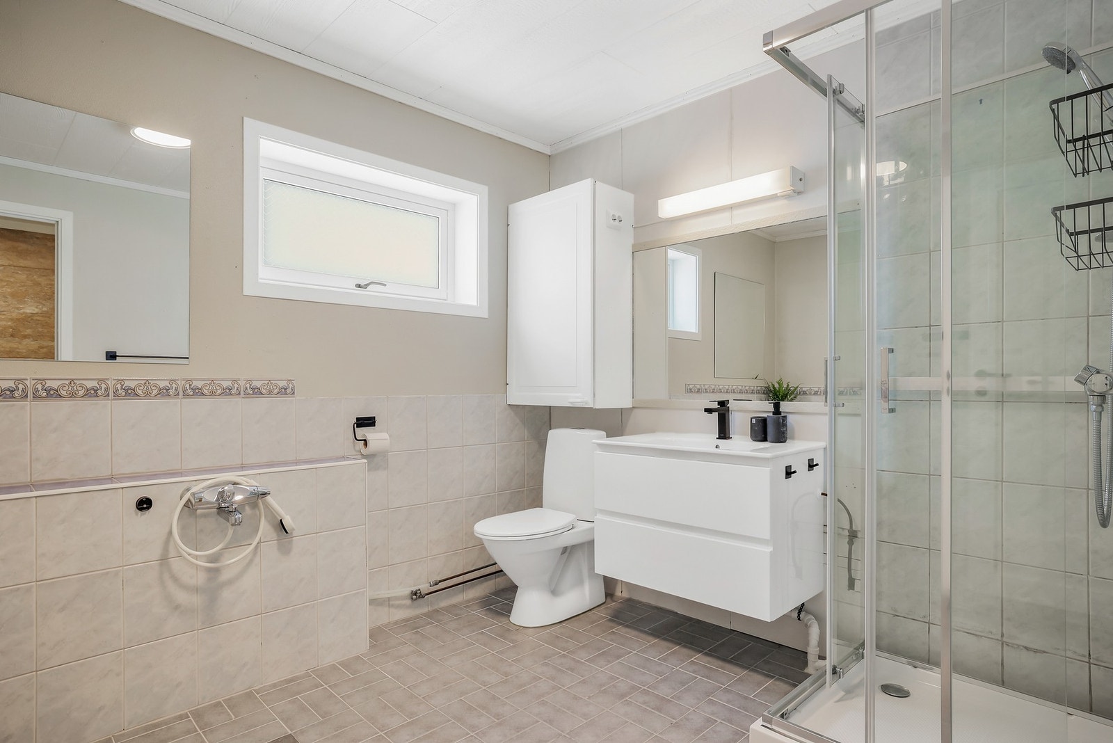 Rommet har en praktisk vegghengt baderomsinnredning med skuffer, gulvstående toalett og dusjkabinett. Galleribilde