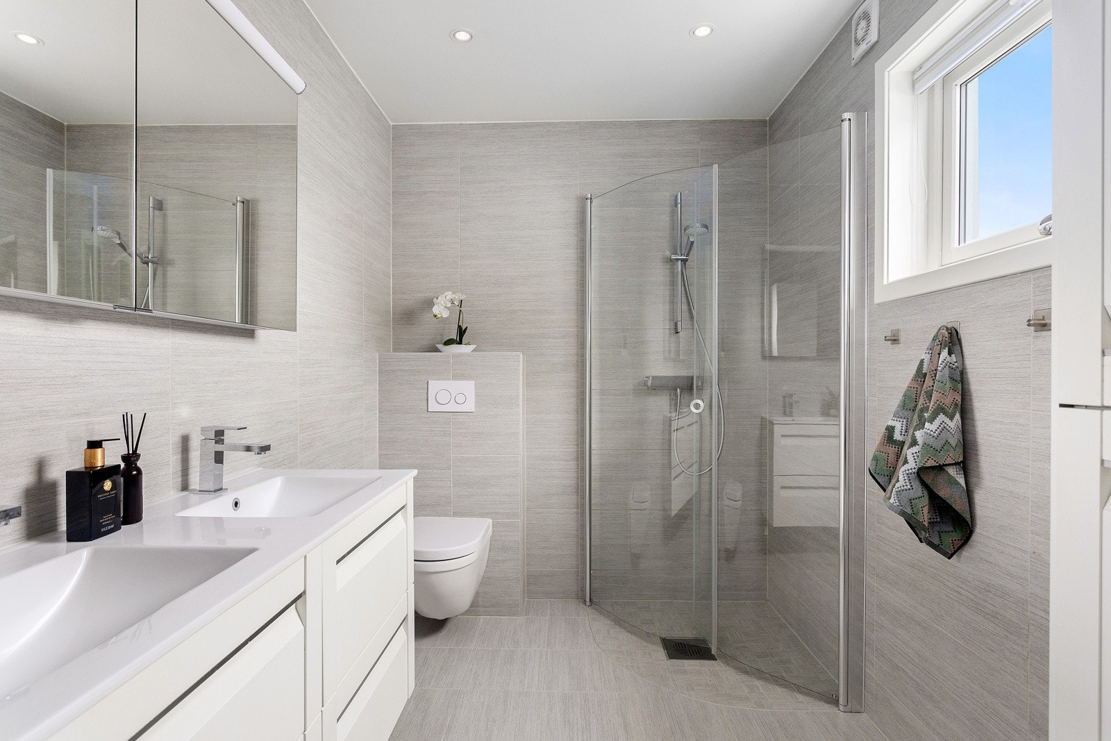 Meget pent flislagt bad fra 2016 med varmekabler - Innredningen består av dusjhjørne med innfellbare dusjdører, vegghengt WC, dobbel servant med underskap og speilskap Galleribilde