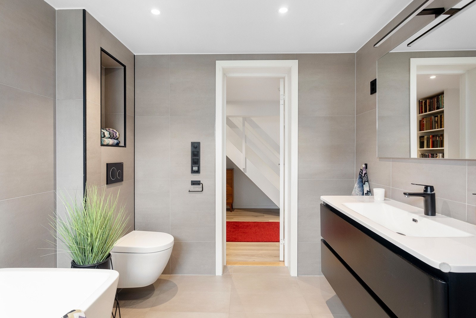 Badet er utstyrt med badekar, dusjsone med innfellbare dusjdører, servant med underskap, overspeil og vegghengt WC Galleribilde