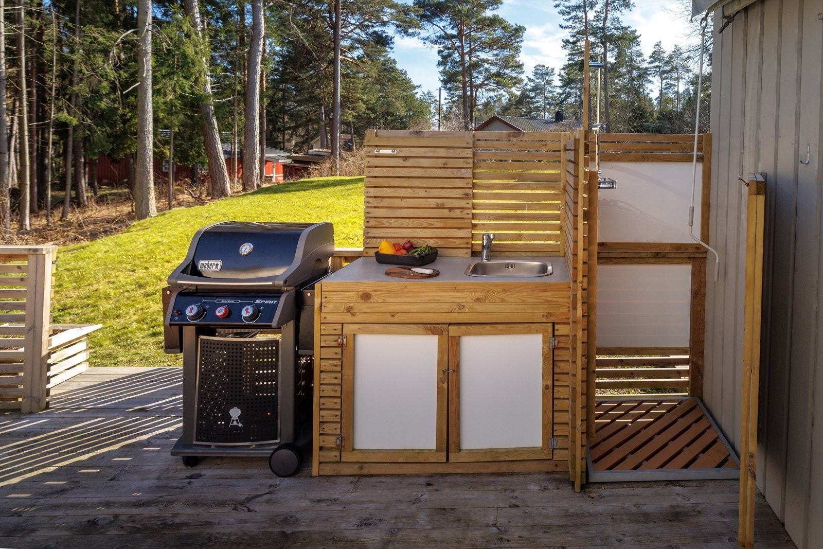 Et enkelt utekjøkken og utedusj er plassert på den sørvendte verandaen. Det er sveisemarkise på vegg. Galleribilde