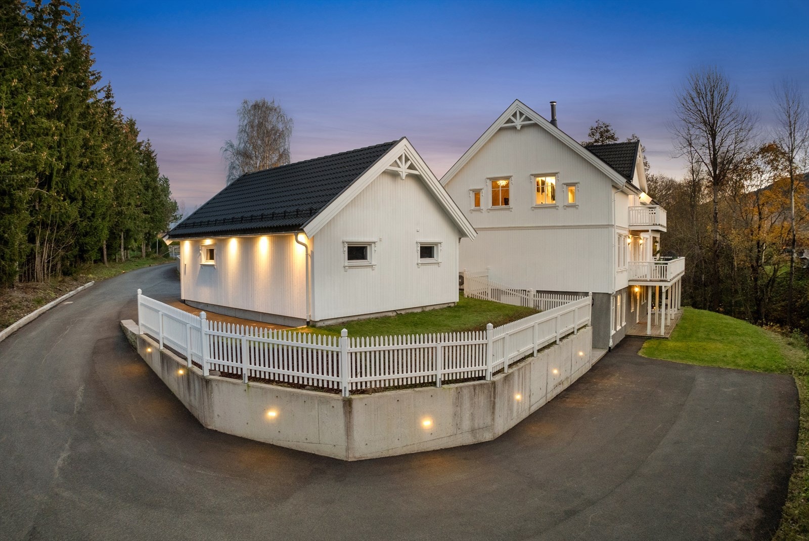 Tomten er betydelig påkostet med asfaltert adkomst, støttemurer, hvite stakittgjerder og innfelt belysning Galleribilde