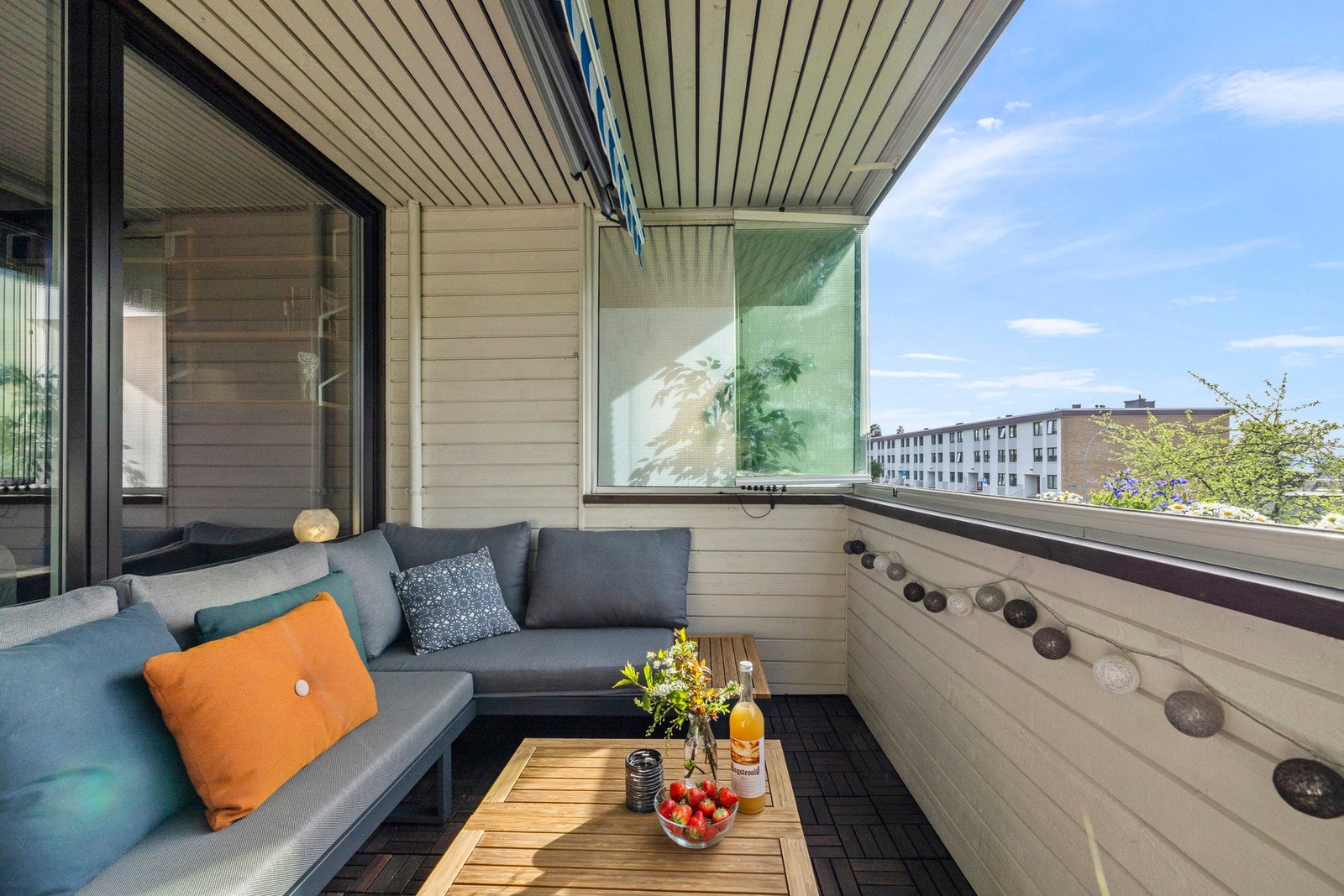 Balkongen har dekke med terrasseheller og rekkverk kledd med trepanel, samt markise Galleribilde