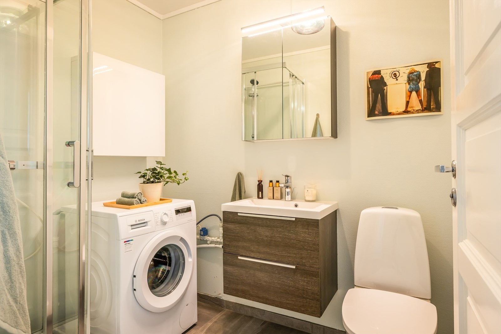 Badet ligger rett ved entré og har flislagt gulv og glassfiberstrie på vegger. Gulv på bad ble oppgradert med ny membran og fliser i 2017. Badet er utstyrt med servant med møblement, dusjkabinett og gulvmontert toalett. Galleribilde