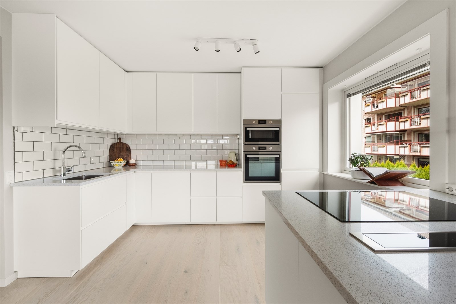 Stilig innredning fra Ikea med hvite, glatte fronter, fliser på vegg over kjøkkenbenk og benkeplate i komposittstein. Galleribilde