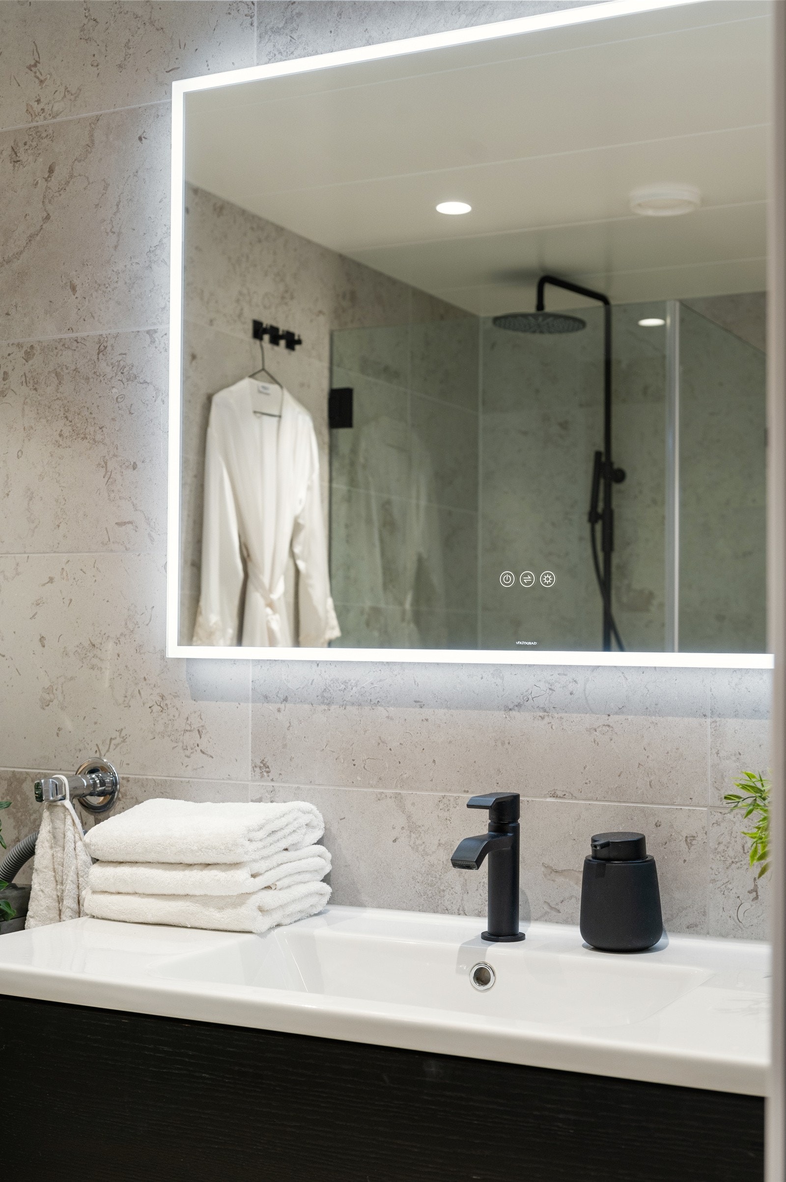 Badet er innredet med heldekkende sevant med skuffeinnredning og speil med integrert belysning Galleribilde