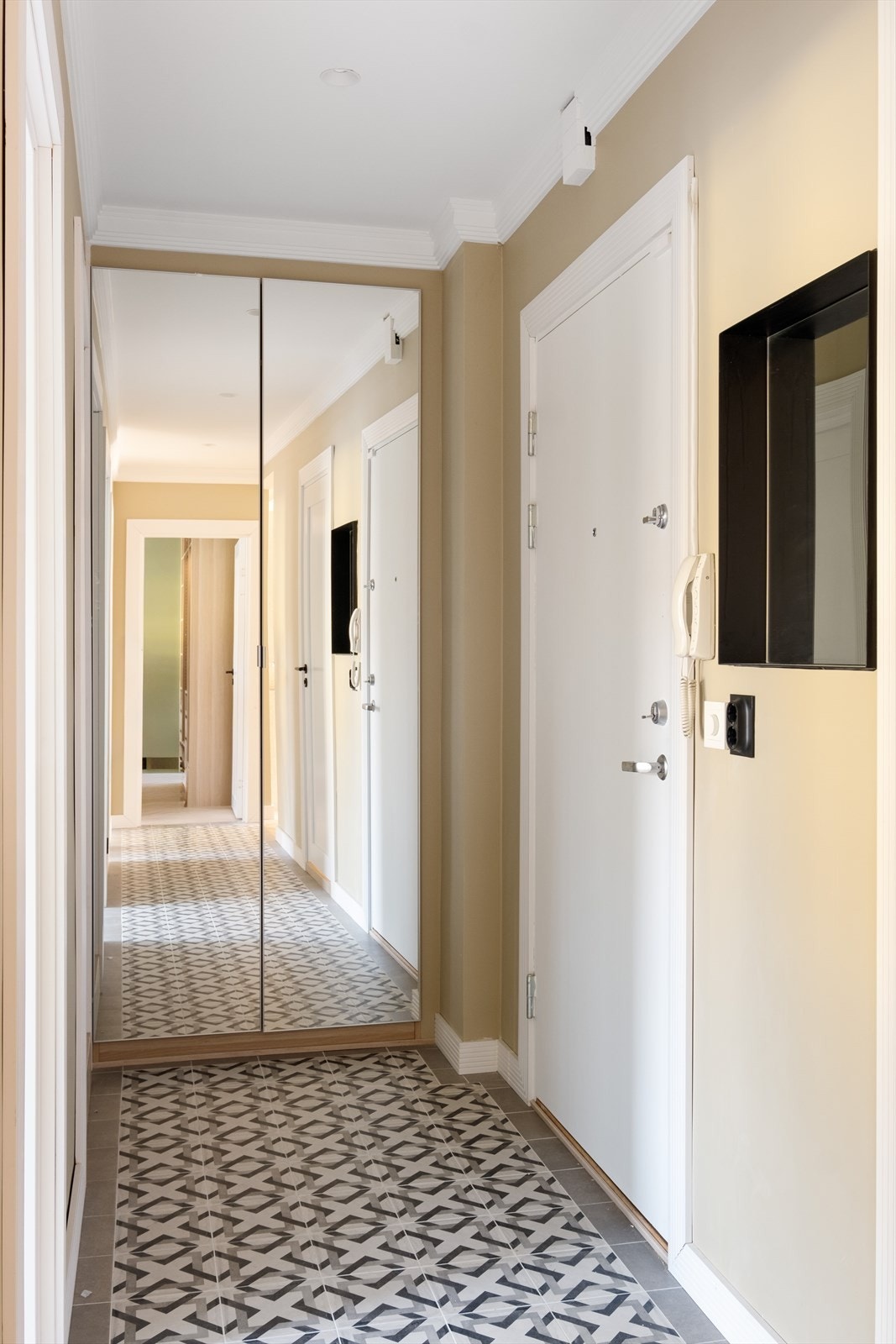 Entréen har lekre, klassiske fliser og et spesialtilpasset garderobeskap som sikrer rikelig med oppbevaring til sko og yttertøy. Praktisk, sort speilnisjé i stål til nøkler og lading av mobil. Galleribilde