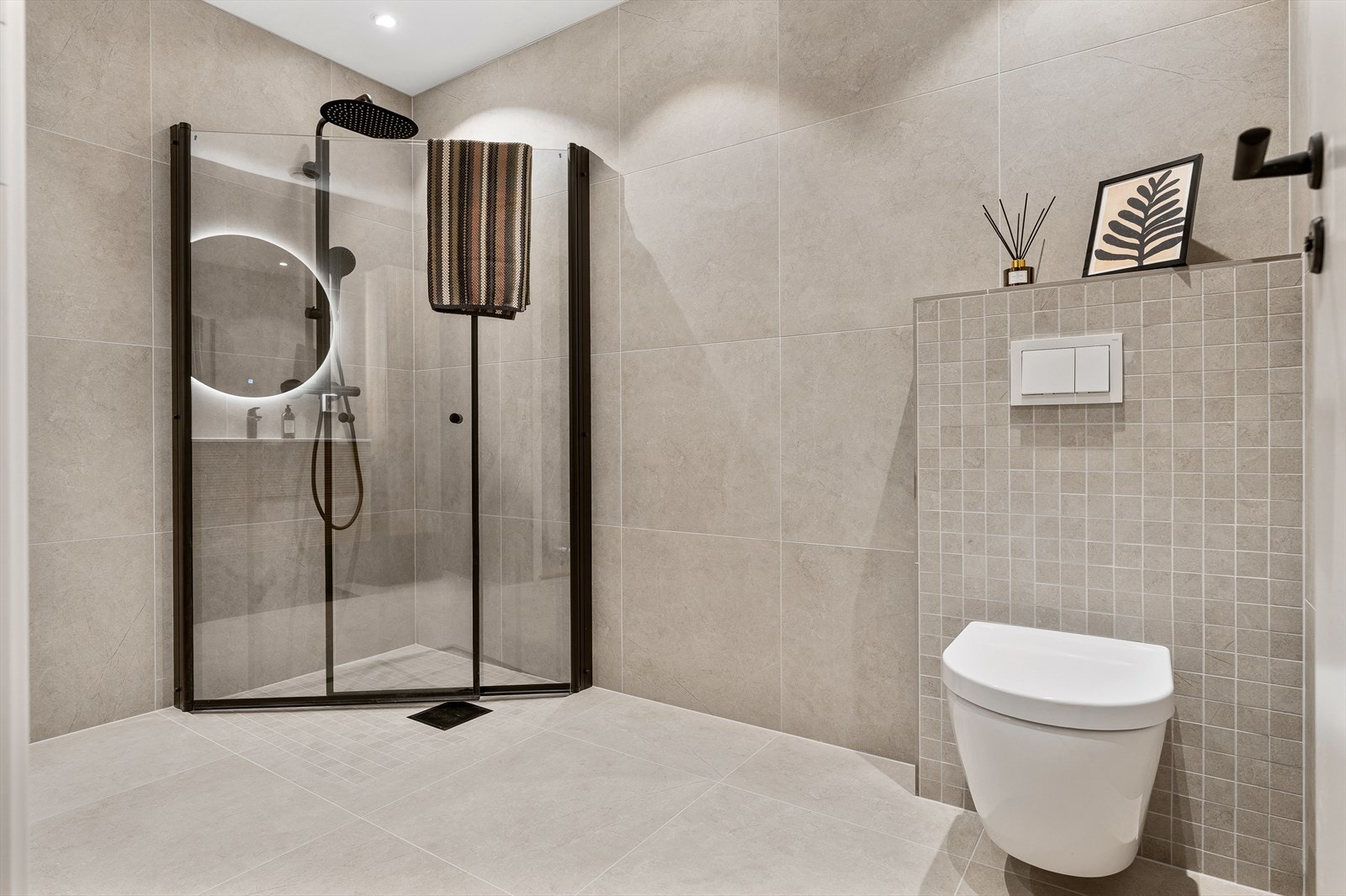 Badet har ellers en flott dusjsone med foldevegger i glass, sort dusjarmatur med behagelig rainshower og vegghengt wc. Galleribilde