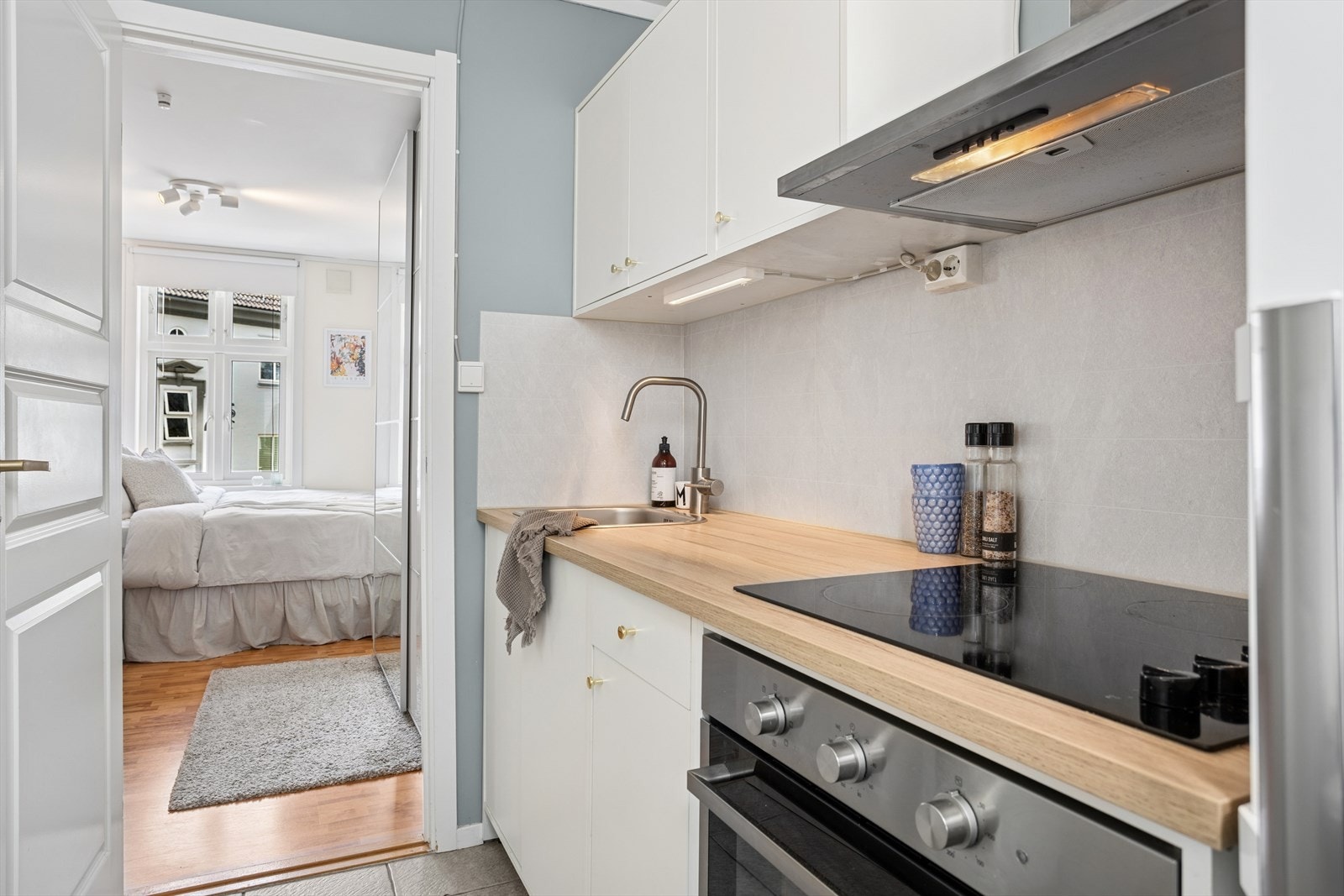 Kjøkkeninnredning har adkomst fra soverommet og er innredet med glatte fronter, skrog av finèr, laminat benkeplater, nedfelt stål vaskebeslag og platetopp. Galleribilde