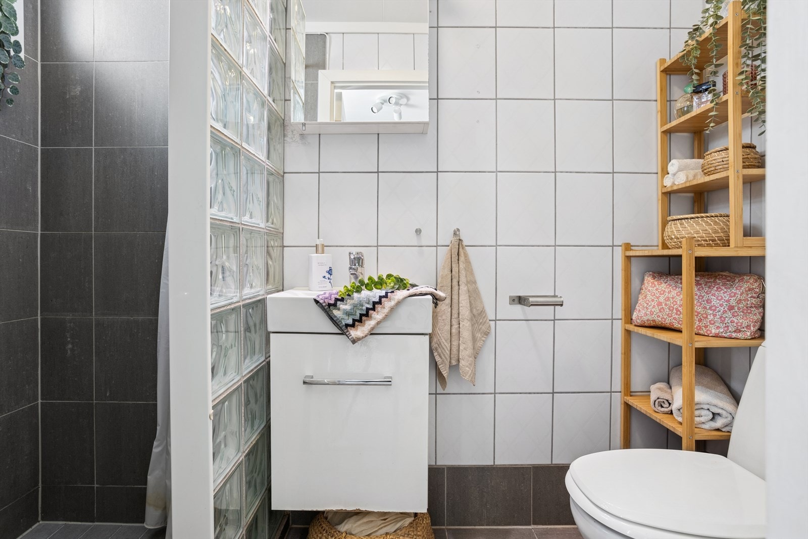 Baderommet har innredning med nedfelt servant, speil over vask, gulvstående toalett og praktisk dusjnisje. Galleribilde