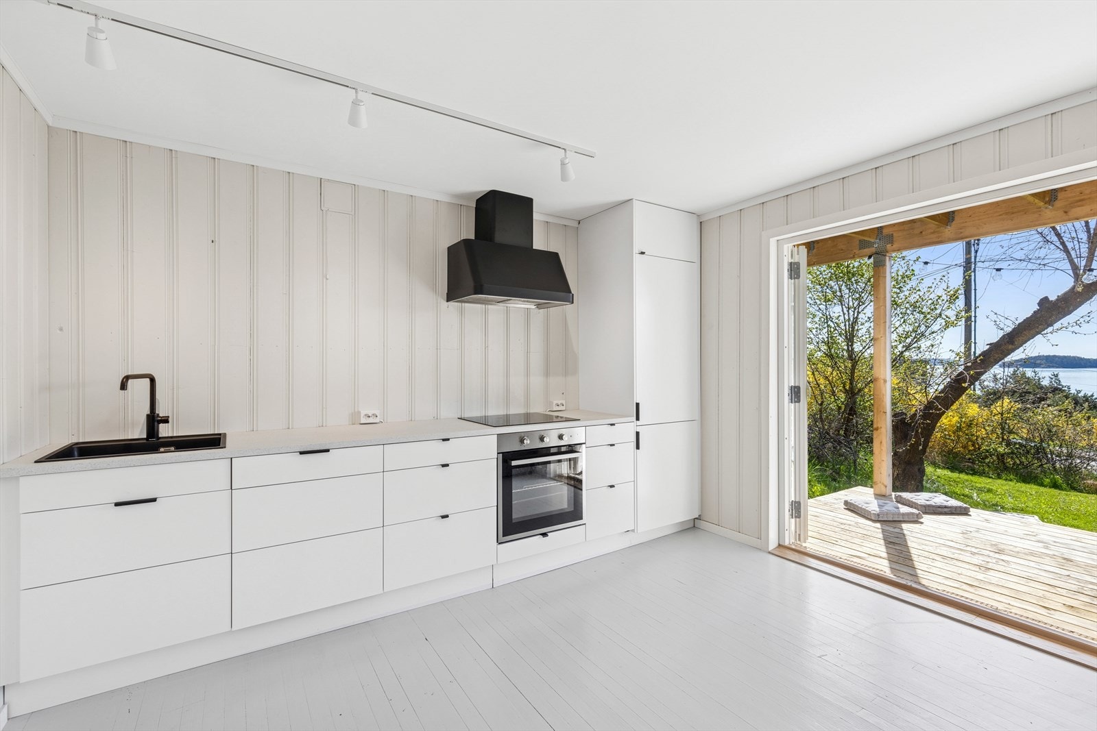 Nyere kjøkken i sokkeletasje med lys kjøkkeninnredning med glatte fronter. Galleribilde