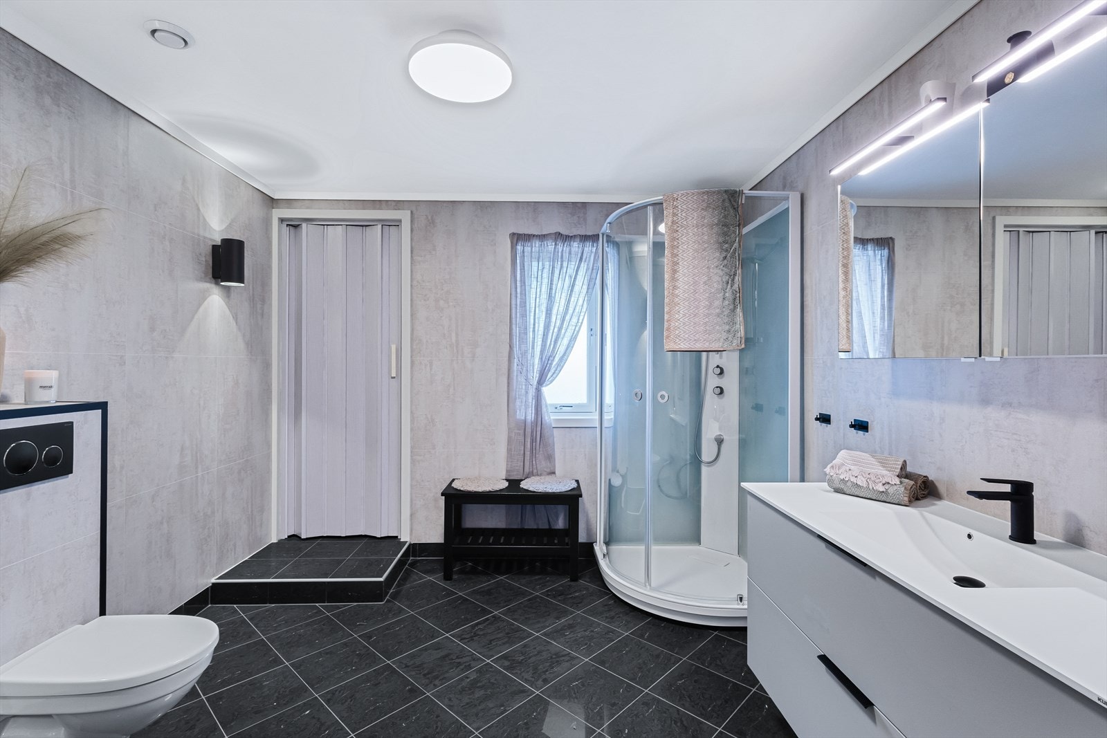 Badet på 9,5 m² har flislagt gulv med termostatstyrte varmekabler, baderomsplater på vegger og malt platekledning i himling Galleribilde