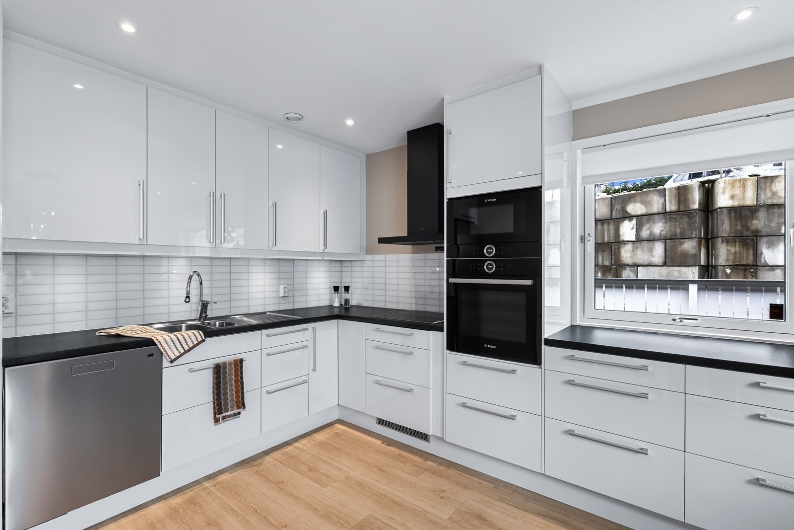 Stilrent og lekkert design med hvite, glatte fronter og laminert benkeplate med planlimt kjøkkenbeslag. Galleribilde