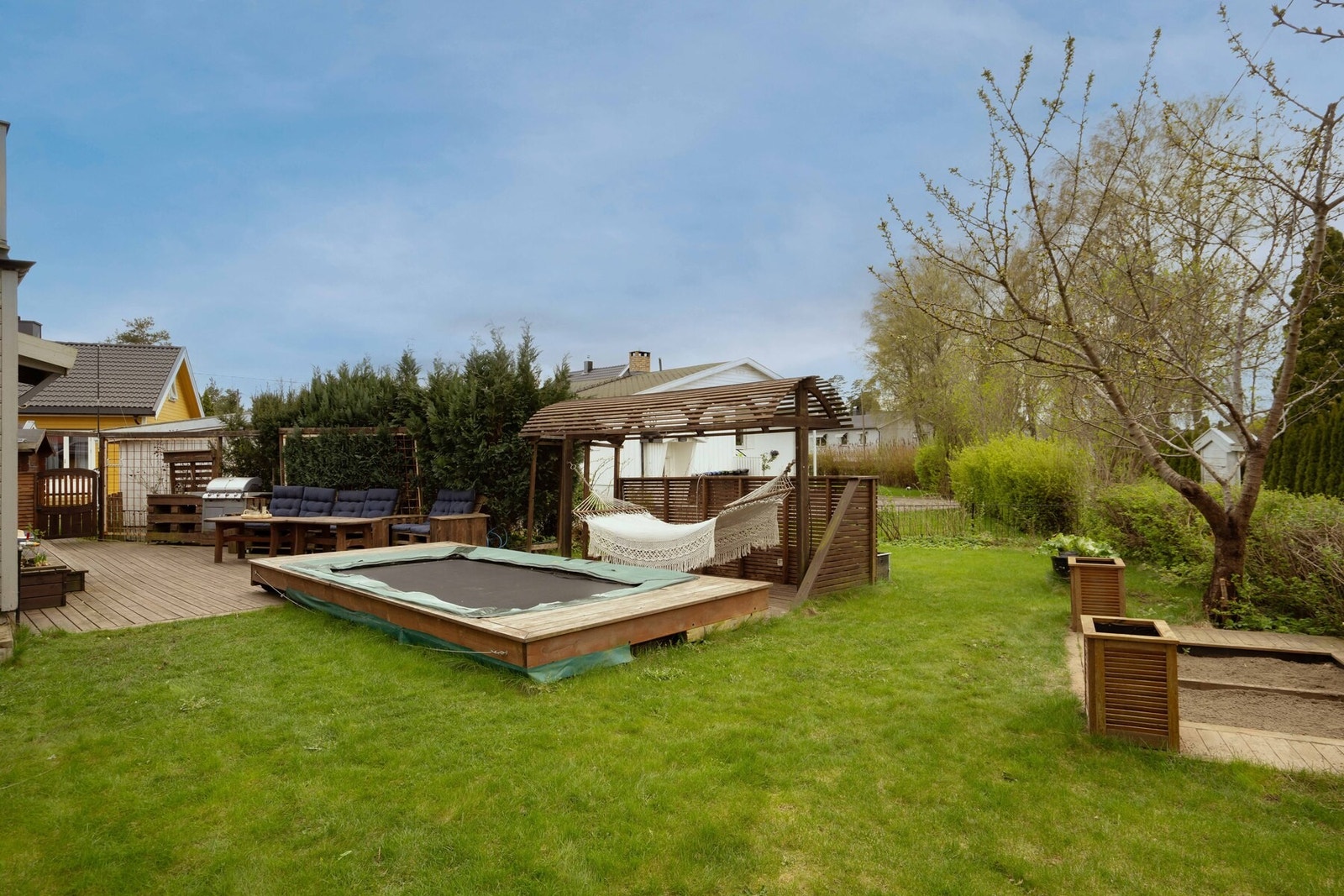 Trivelig opparbeidet med lekeareal, gressplen og sitteplass - under trampolinen skjuler det seg et lite basseng! Galleribilde
